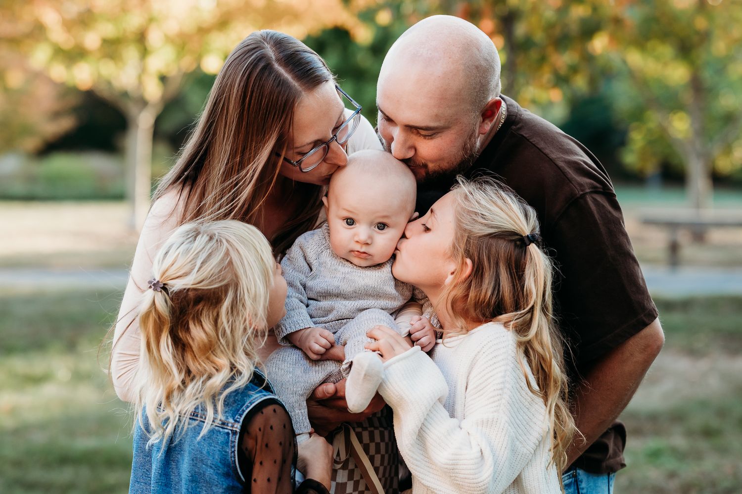 A loving family shares tender moments together in a sunny outdoor setting during a fall photo session in Plainfield, Indiana.