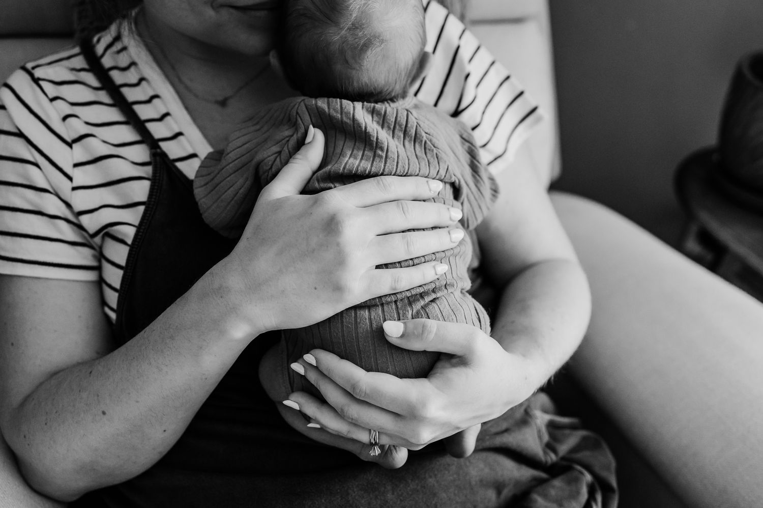 A black and white image with mom holding infant during Indiana newborn photoshoot at home.