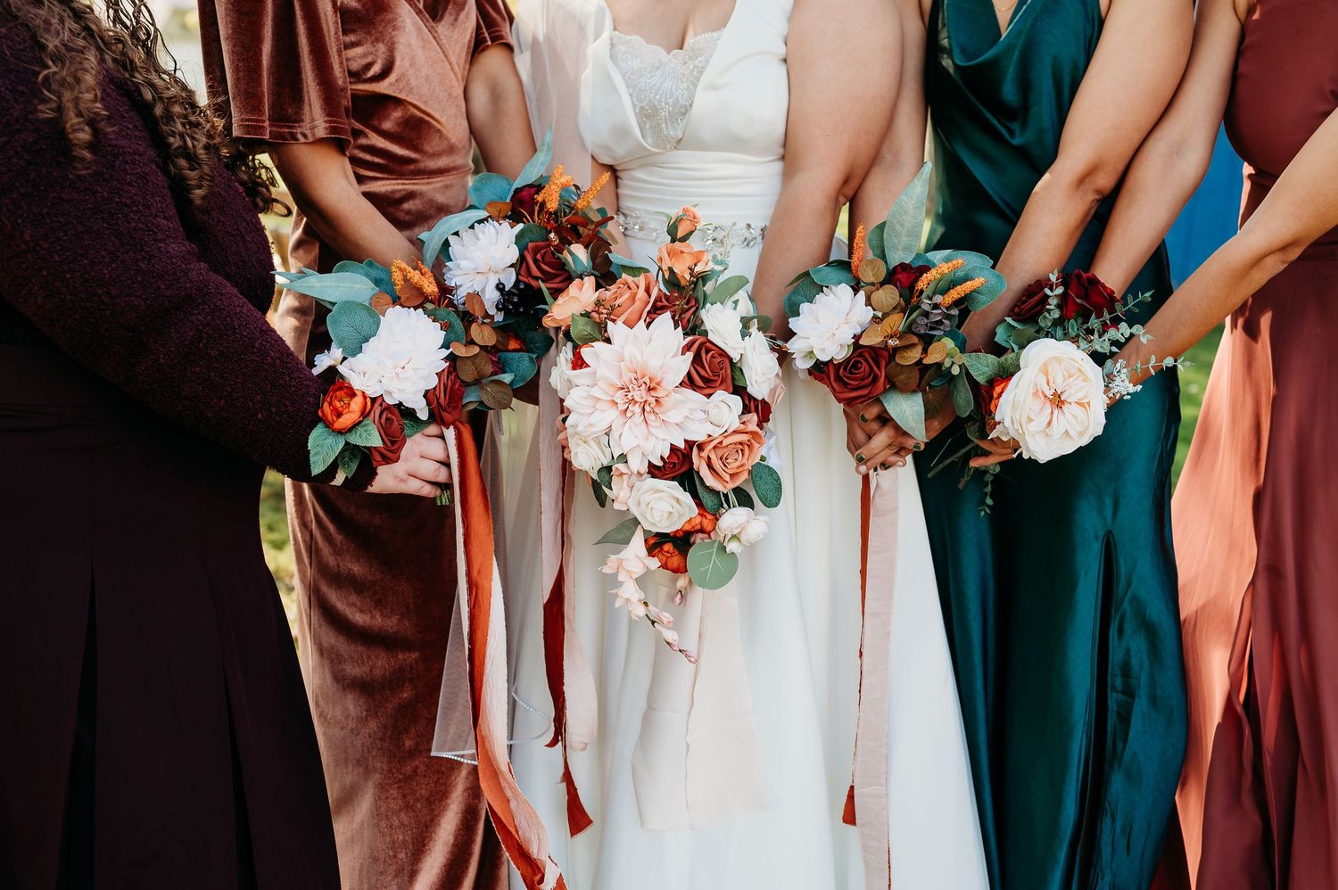 Wedding party stands in line holding coral and white floral bouquets with bridesmaids in teal dresses.
