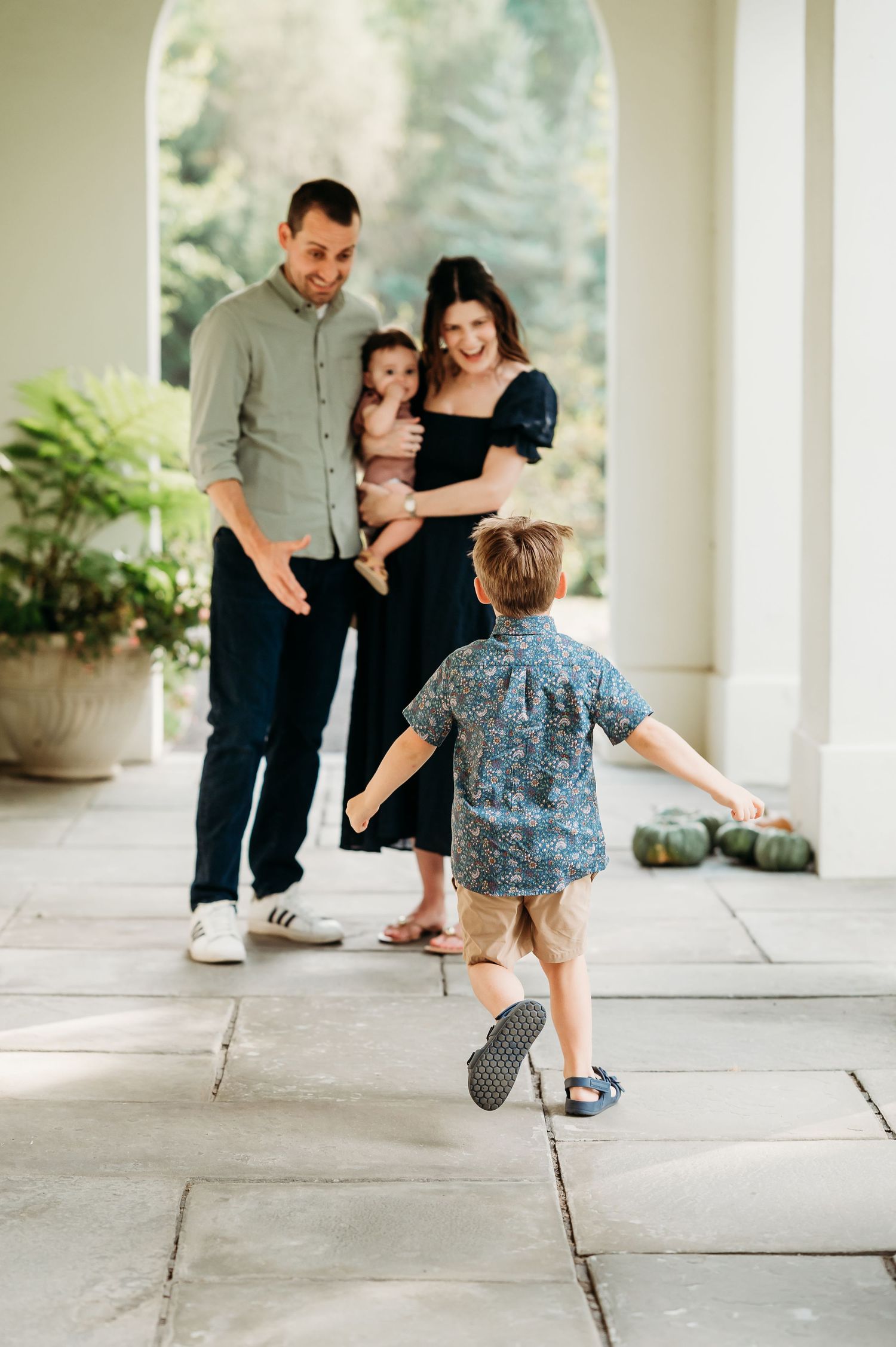 A joyful family moment captured at Newfields as a young boy runs playfully towards family during Indianapolis photo session with Sara House.
