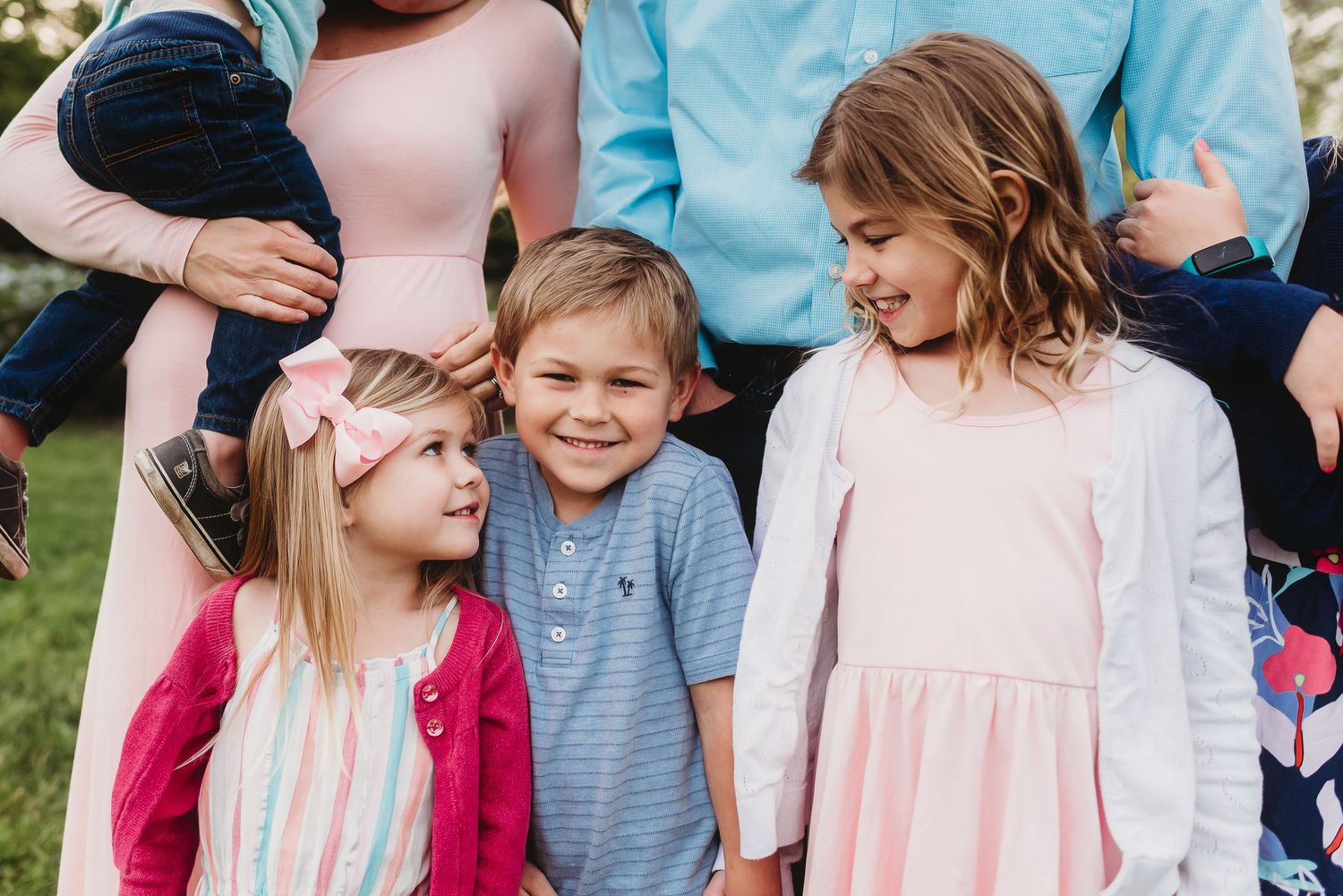 A group of children in coordinatingl attire laugh and play together outdoors on a sunny day.