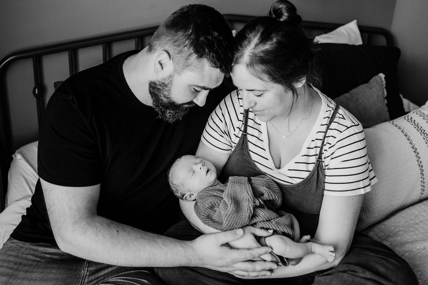 Black and white photo showing parents and baby snuggling at home during photo session with Indianapolis family and newborn photographer.