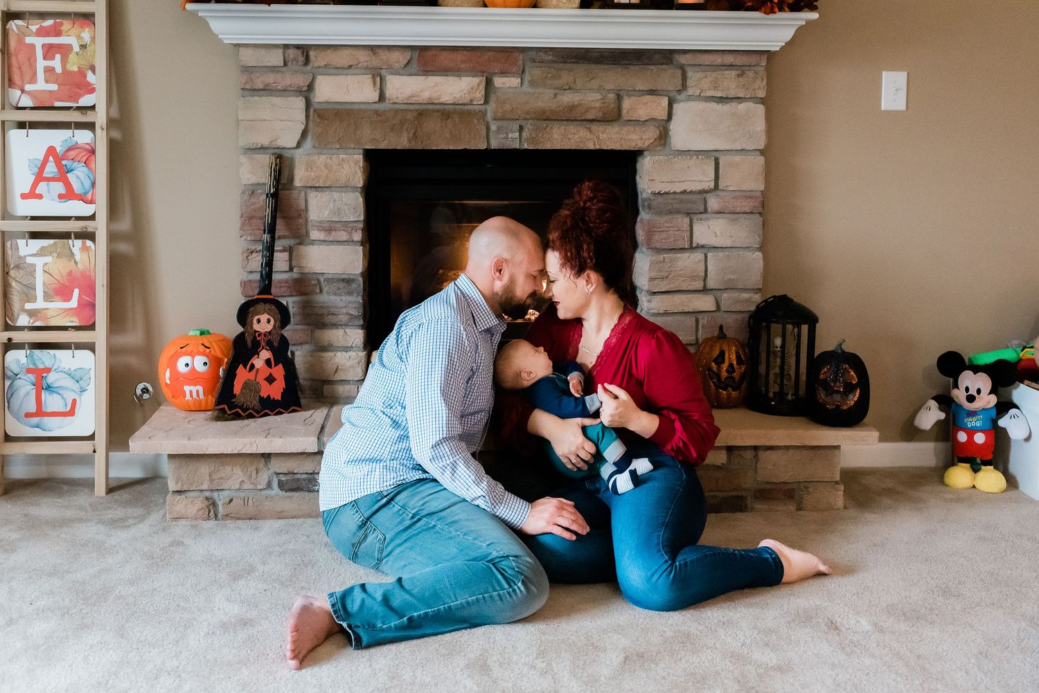 Family lounging near brick fireplace with Disney toys scattered around during newborn photos at Avon, Indiana, home.
