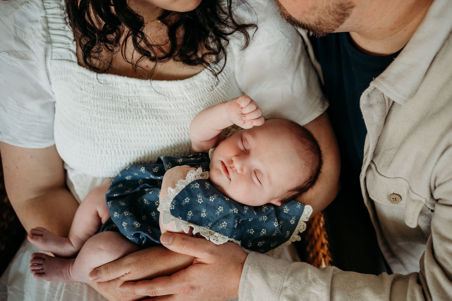 Sleeping baby girl stretches while lying in mother's arms during Westfield, Indiana, in-home newborn session.