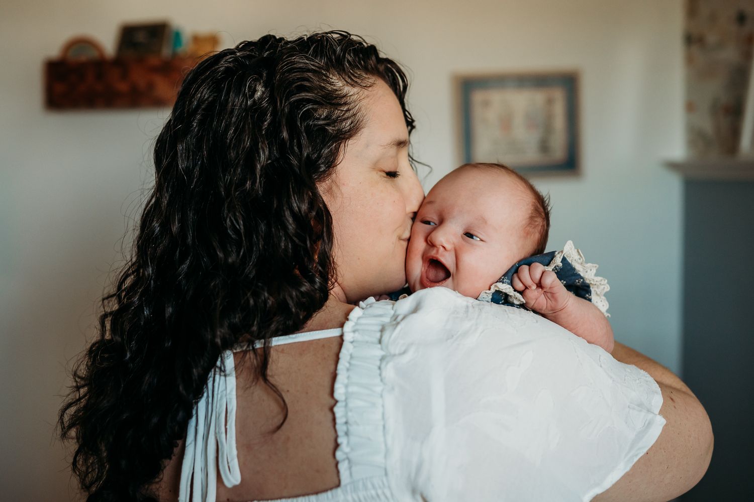 Westfield, Indiana, mom kisses baby girl during newborn photoshoot in their home.
