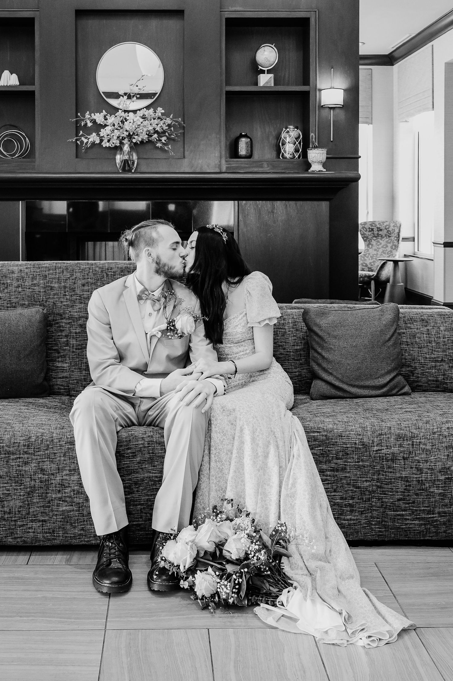A black and white photo of a couple sitting together in an elegant venue with dark walls and wooden floors.