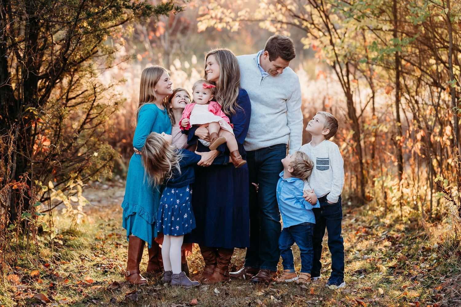 A family gathers for outdoor family photos among golden fall foliage at sunset at Ritchey Woods Nature Preserve in Fishers, Indiana.