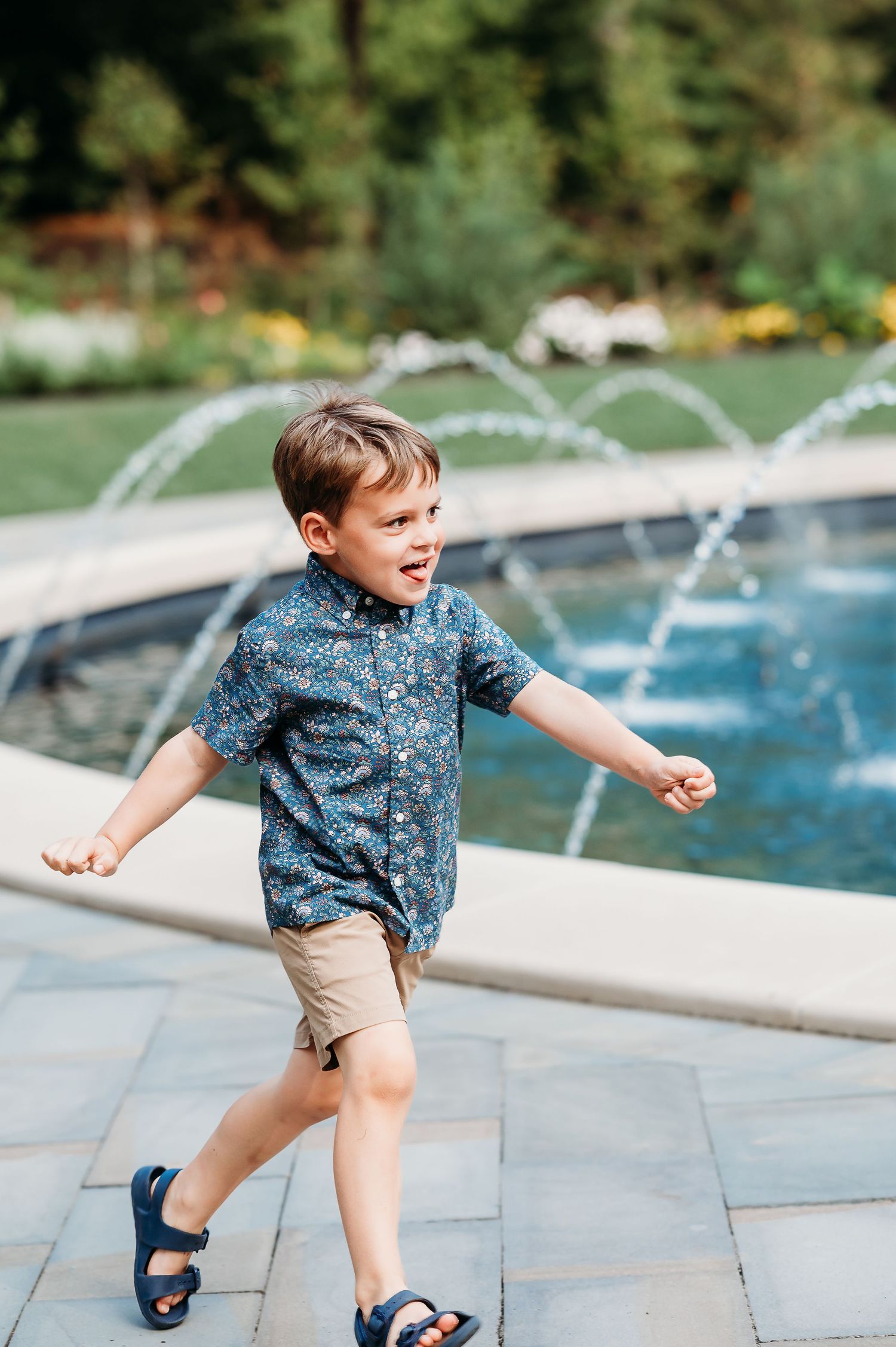 A child in a blue patterned shirt and khaki shorts plays near fountain at Newfields during Indianapolis photoshoot.