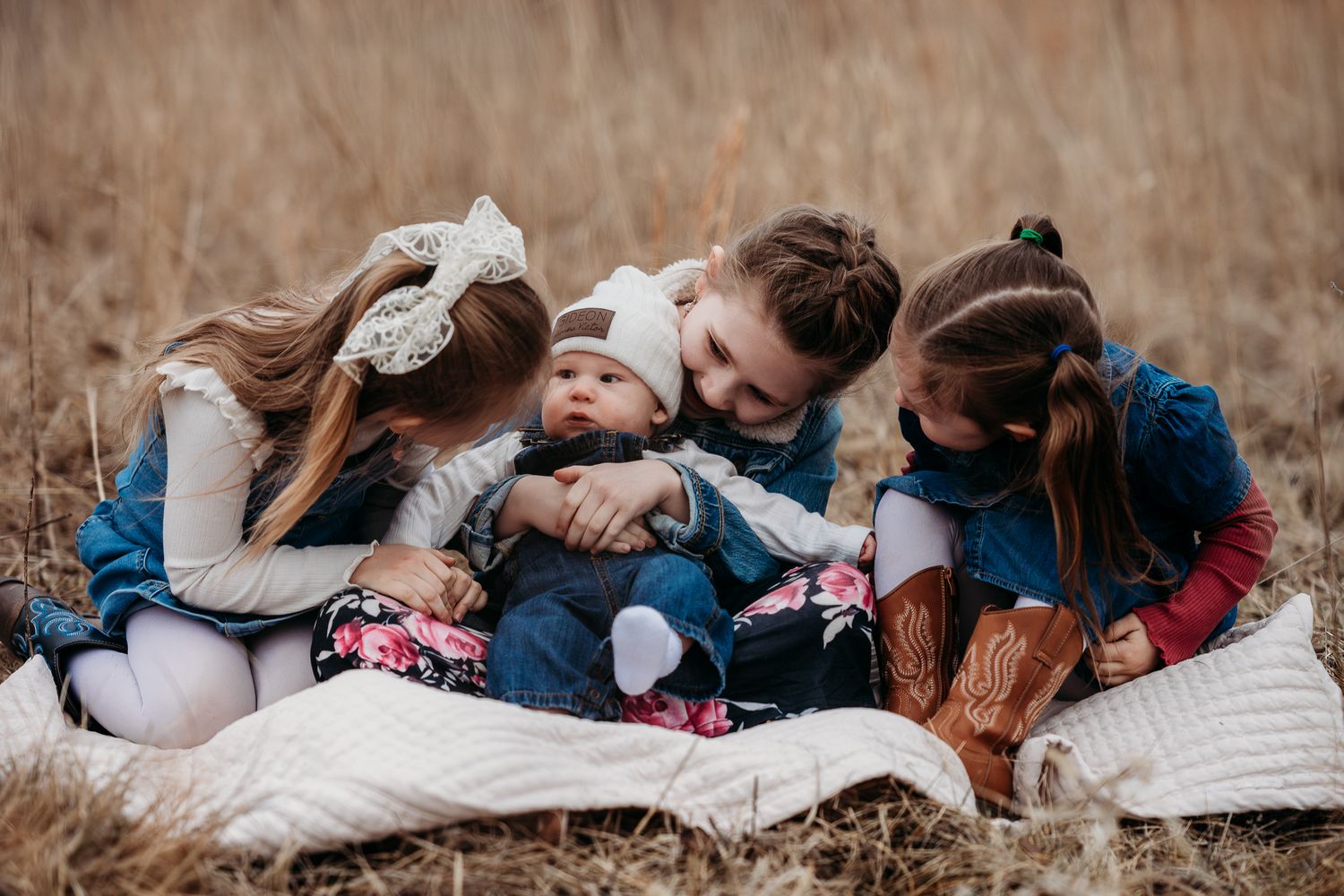 A group of siblings snuggle together on a blanket in a field of brown grass during an Avon, Indiana, outdoor photoshoot.