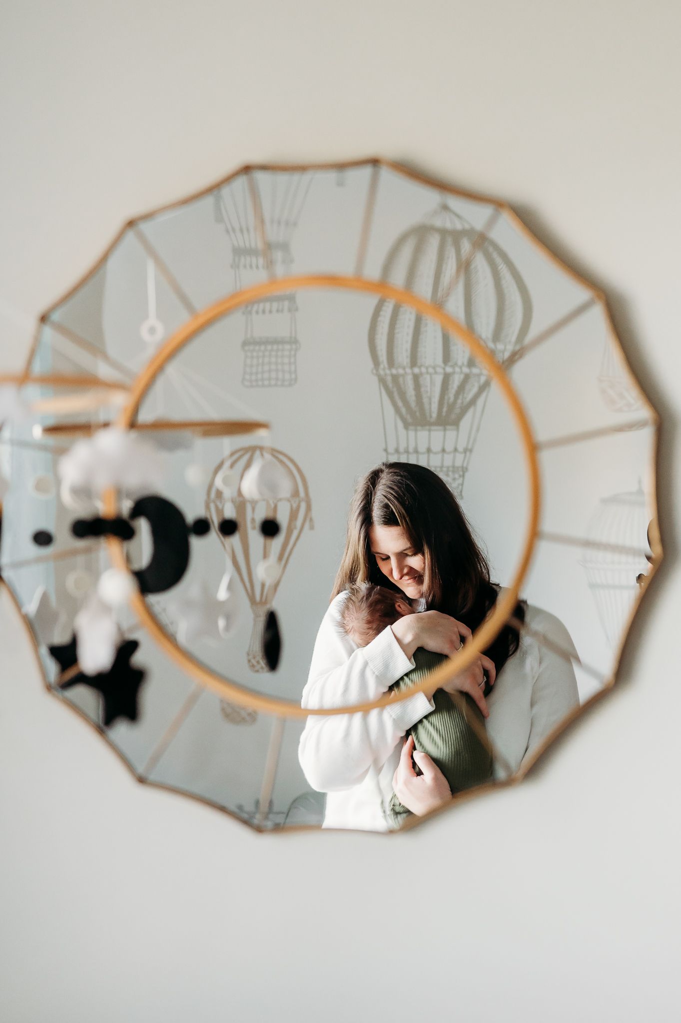 Mirror reflection in a unique circular frame with hot air balloon decoration pattern against white wall.