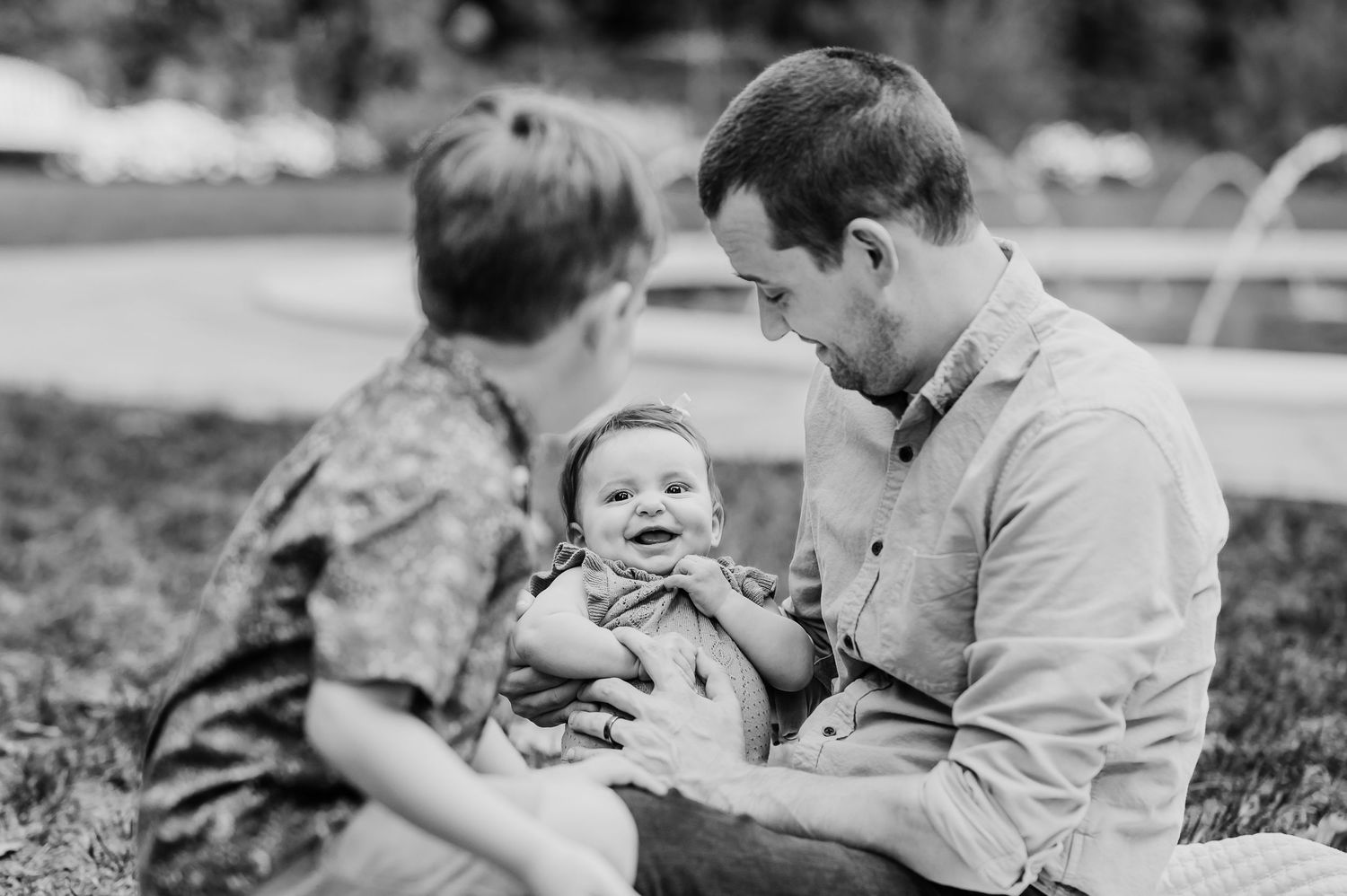 Black and white photo showing tender moment between a dad young children outdoors at Newfields in Indianapolis.