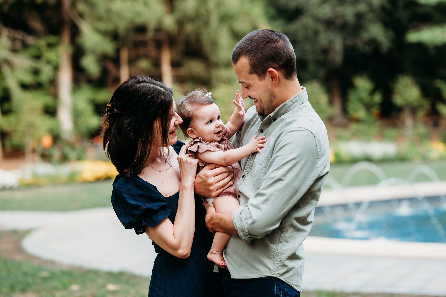 Family shares tender moments together outdoors by fountain at Newfields in Indianapolis.