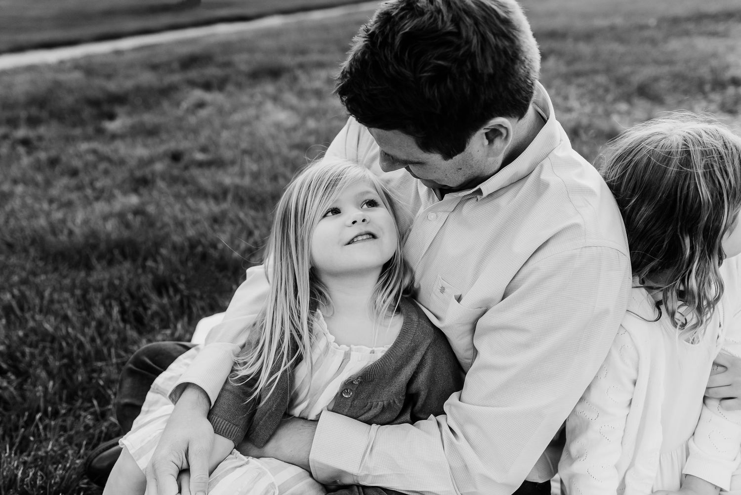 A family shares tender moments together while sitting in a grassy field at sunset in Friendship Gardens in Plainfield, Indiana.