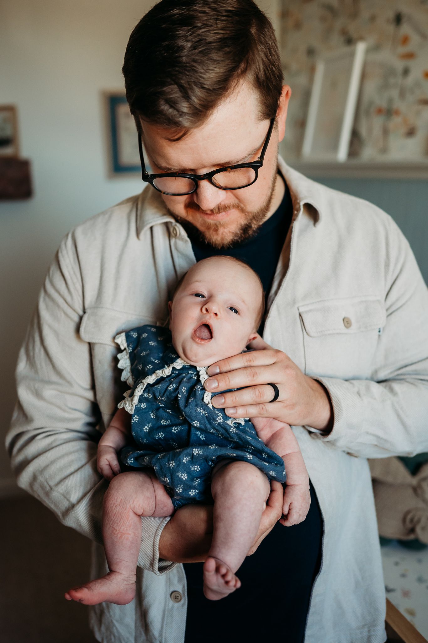 A tender moment between dad and baby wearing a blue floral outfit as they share a quiet moment in their Westfield home.