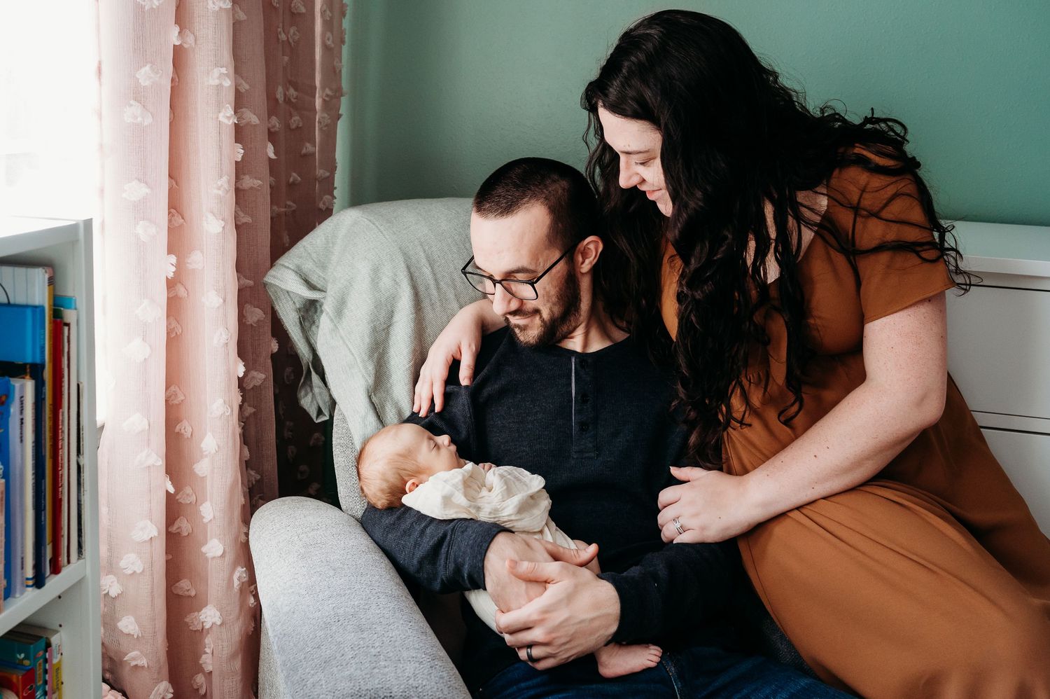A Noblesville couple cradles their newborn baby in a tender moment during an intimate lifestyle photography session.