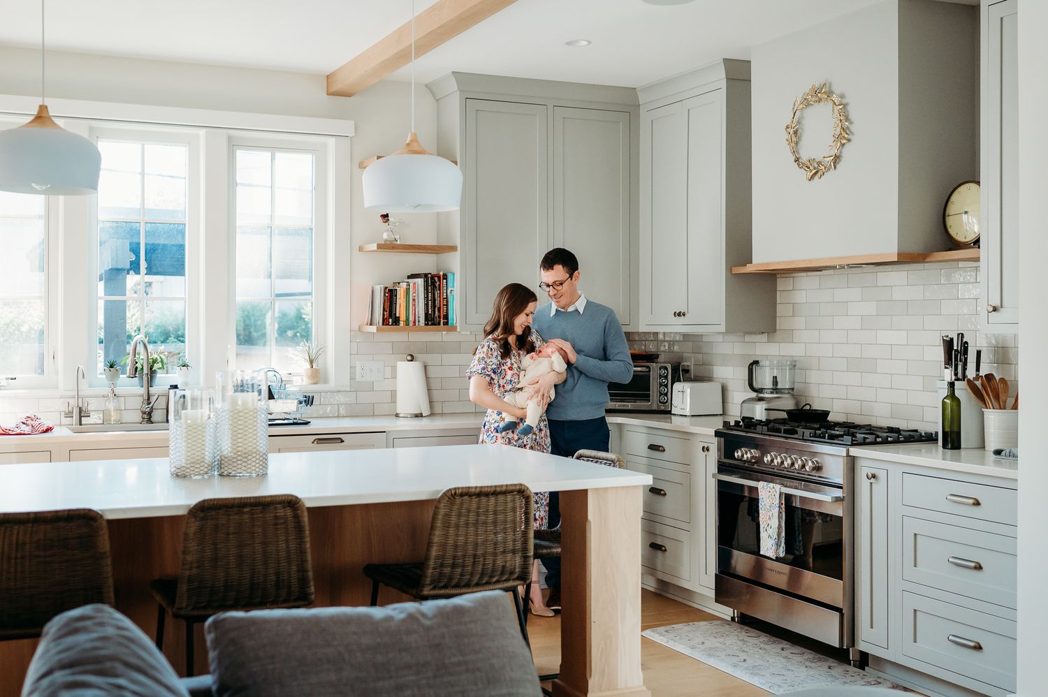 Mom and dad hold baby boy in a bright modern farmhouse kitchen during newborn photoshoot in Westfield, Indiana.