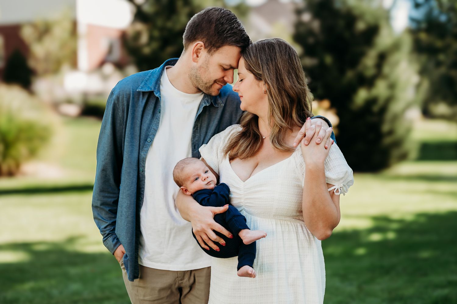 A couple shares quiet moments in a Carmel, Indiana, garden setting while holding their newborn baby.