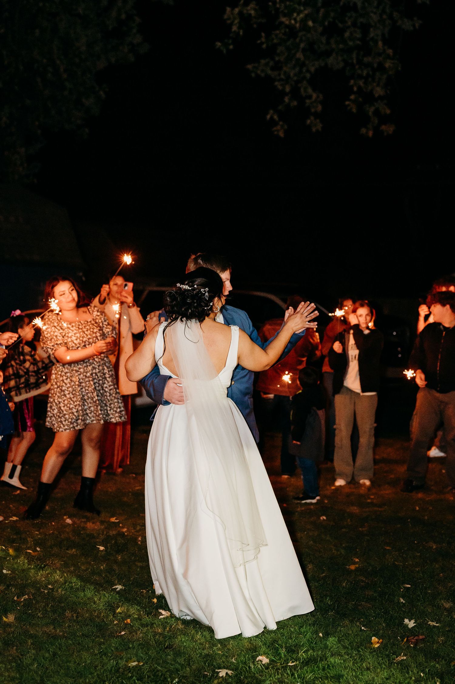 Festive nighttime celebration with sparklers creating a magical atmosphere on a grassy lawn.