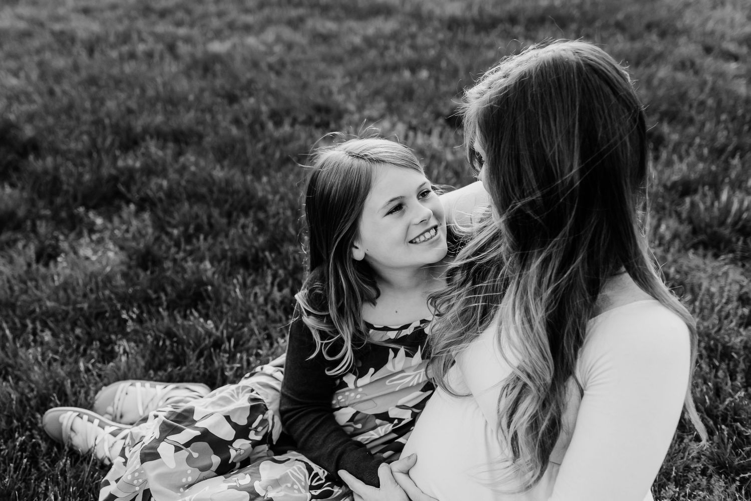 Mom and daughter share a joyful moment together while sitting outdoors in black and white photography.