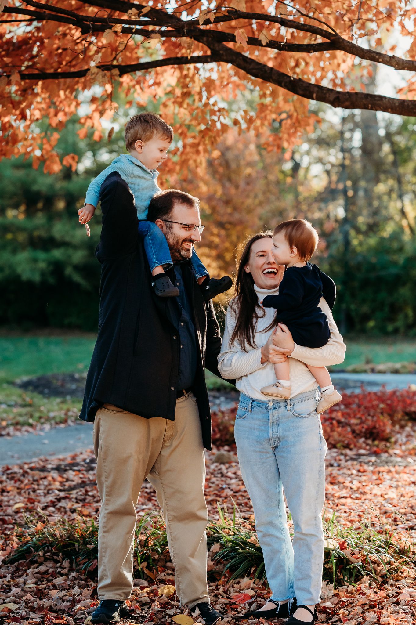 A heartwarming family photoshoot in a Plainfield park filled with fallen autumn leaves and golden light.