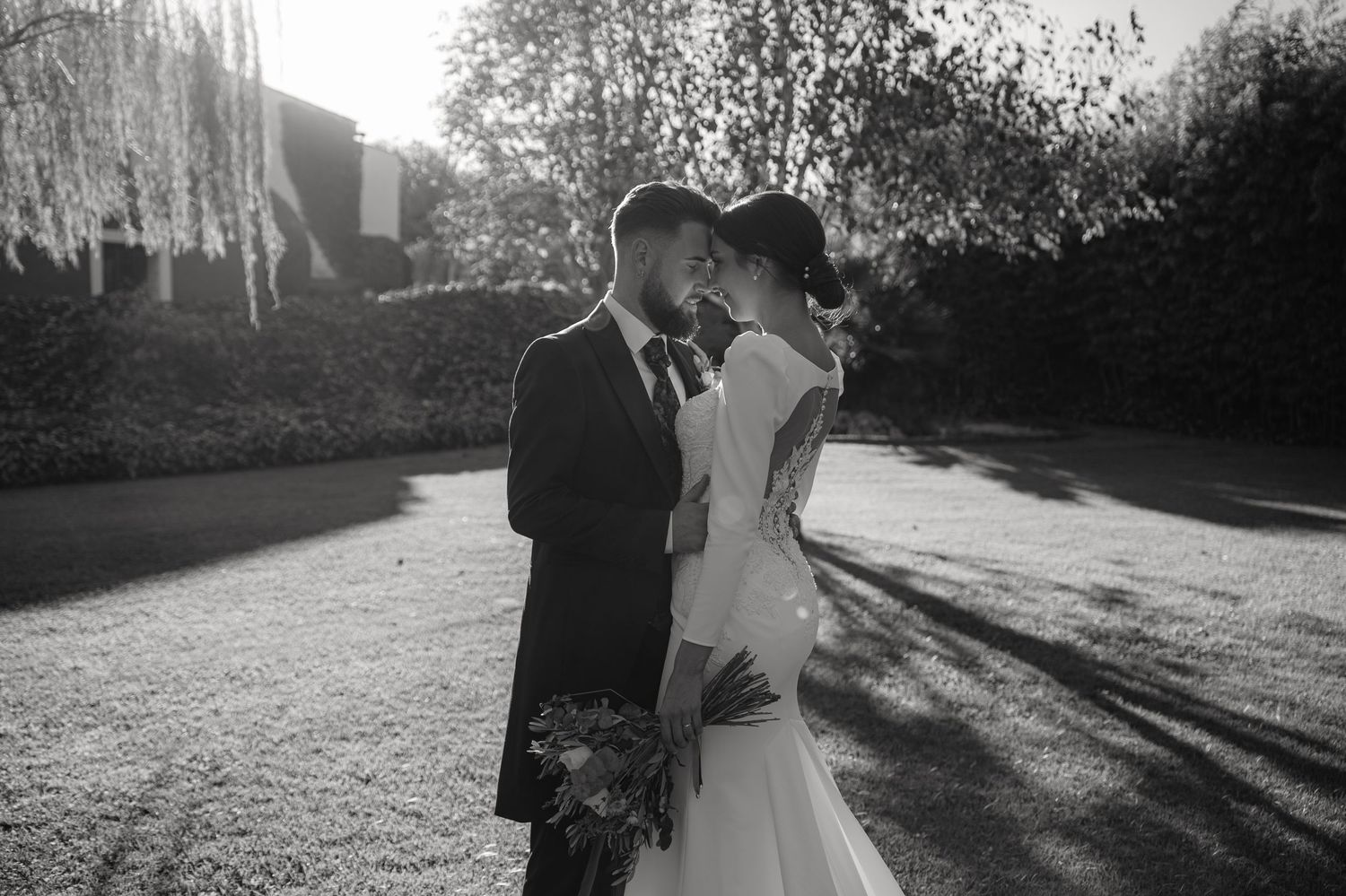 Romantic black and white portrait of newlyweds embracing at sunset.
