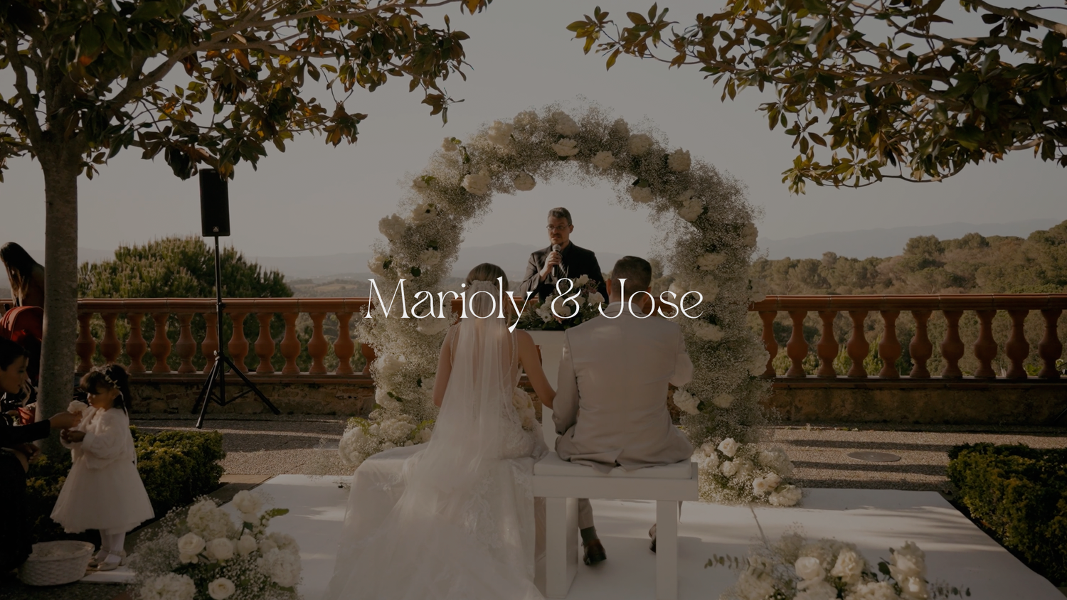 An elegant outdoor wedding ceremony under a floral arch overlooking a scenic vista.