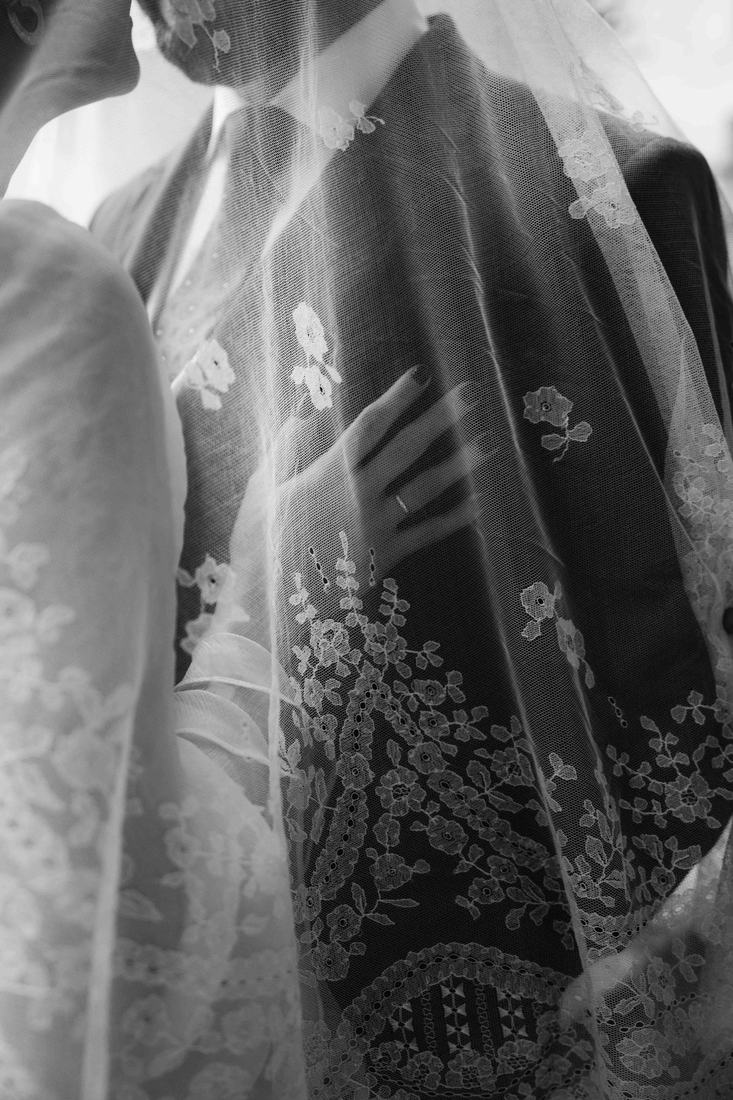 Close-up view of black and white wedding dresses with delicate floral embroidery details hanging on a rack.