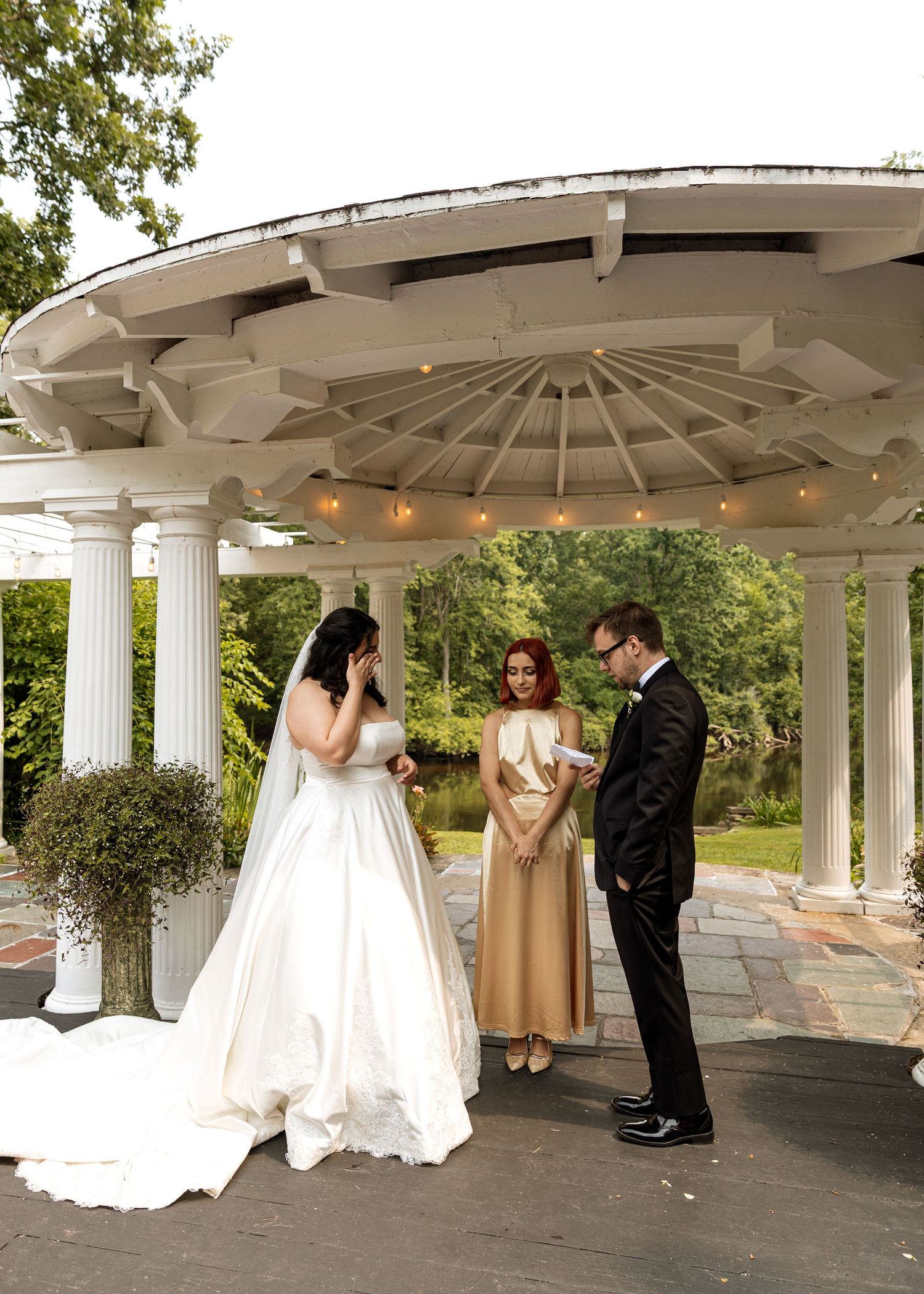 Wedding ceremony moments captured under a white columned gazebo with flowing dress details.