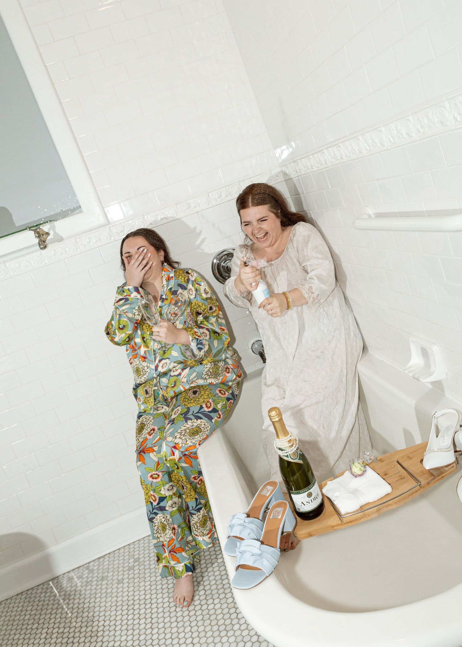 Getting ready scene with wedding preparations in a bright white room with champagne and robes.