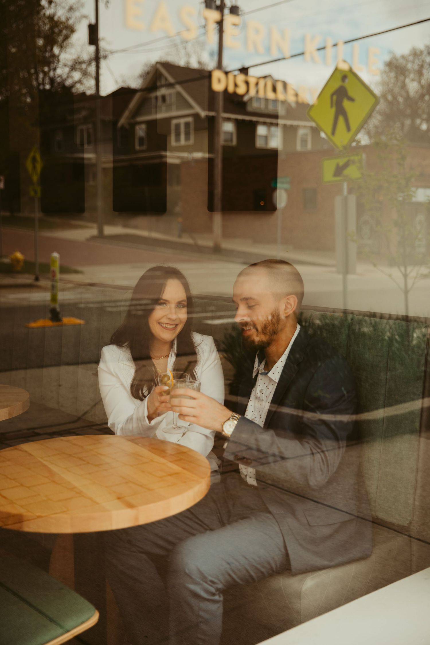 Couple sharing an intimate moment at a cafe table seen through window reflection.