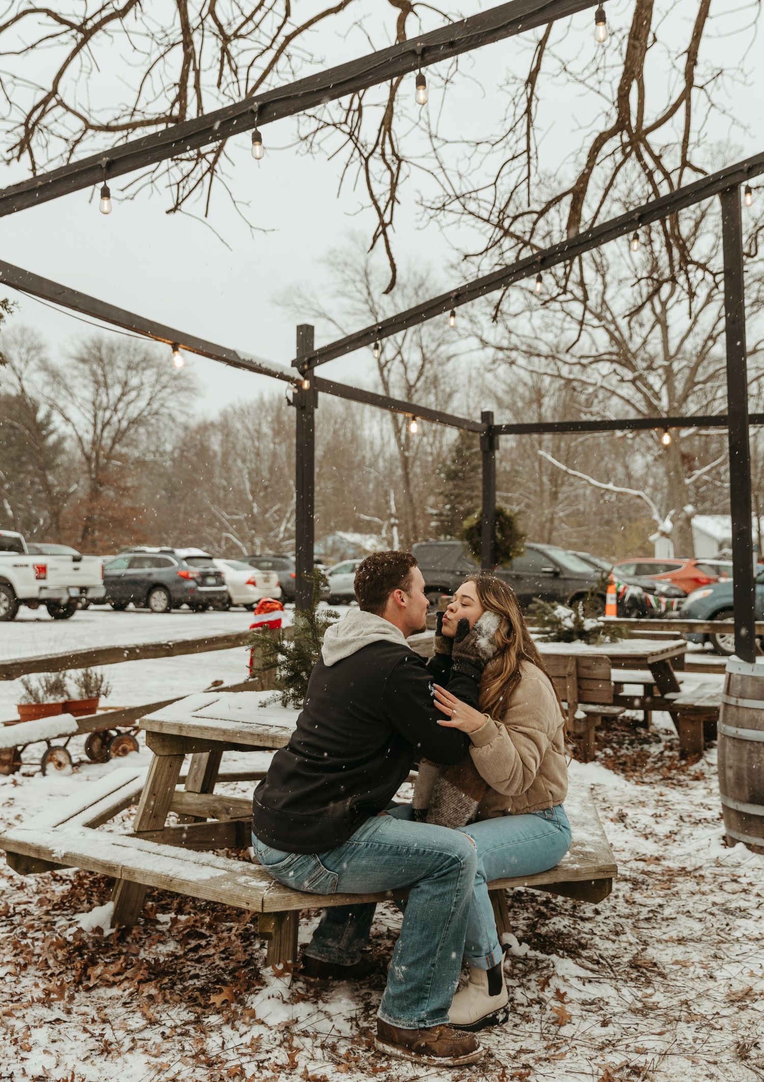 A romantic winter scene with a couple sharing an intimate moment on a snow-covered picnic table.
