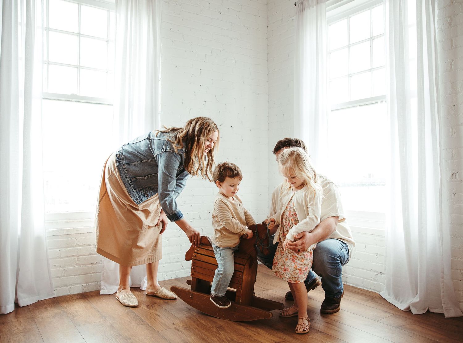 Panoramic view of family playing together in bright white room.
