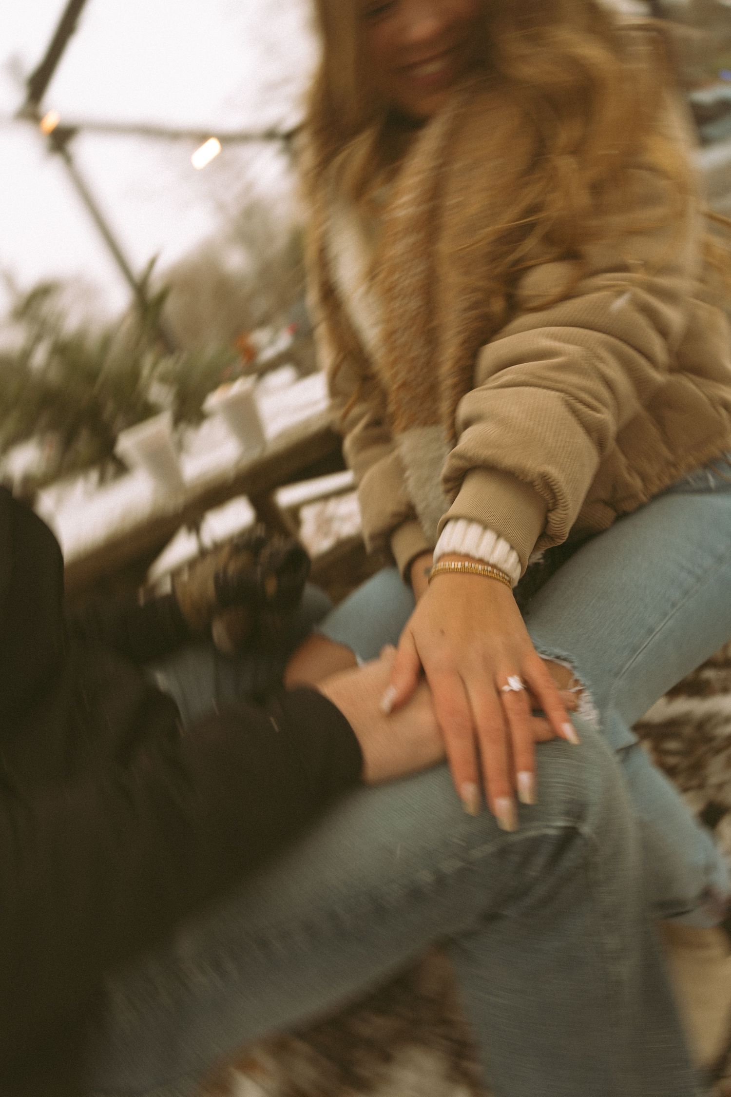 Close-up shot of hands resting on a wooden surface in warm winter clothing.