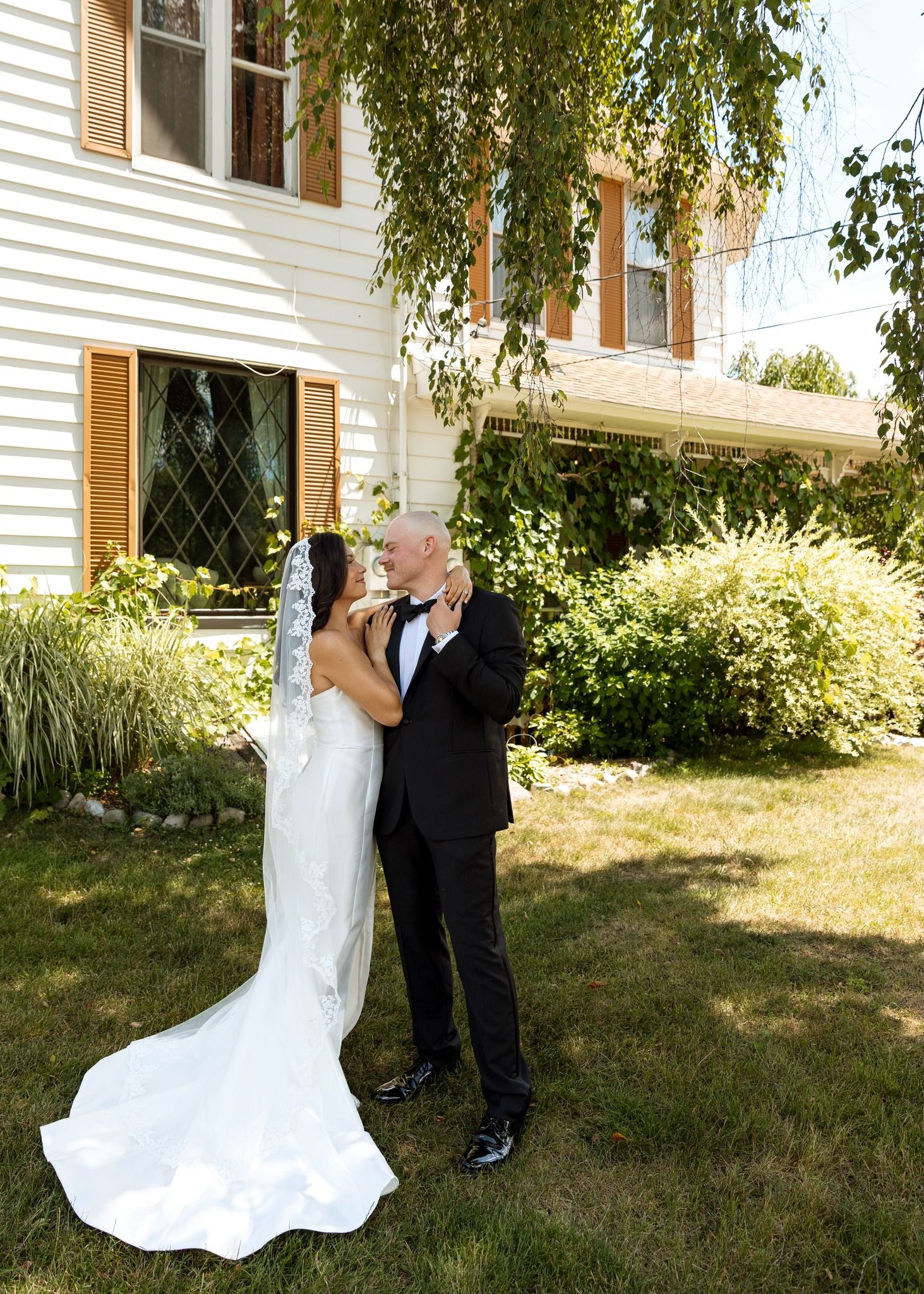 A series of wedding photos capturing a couple dancing and twirling on grass near a white building.