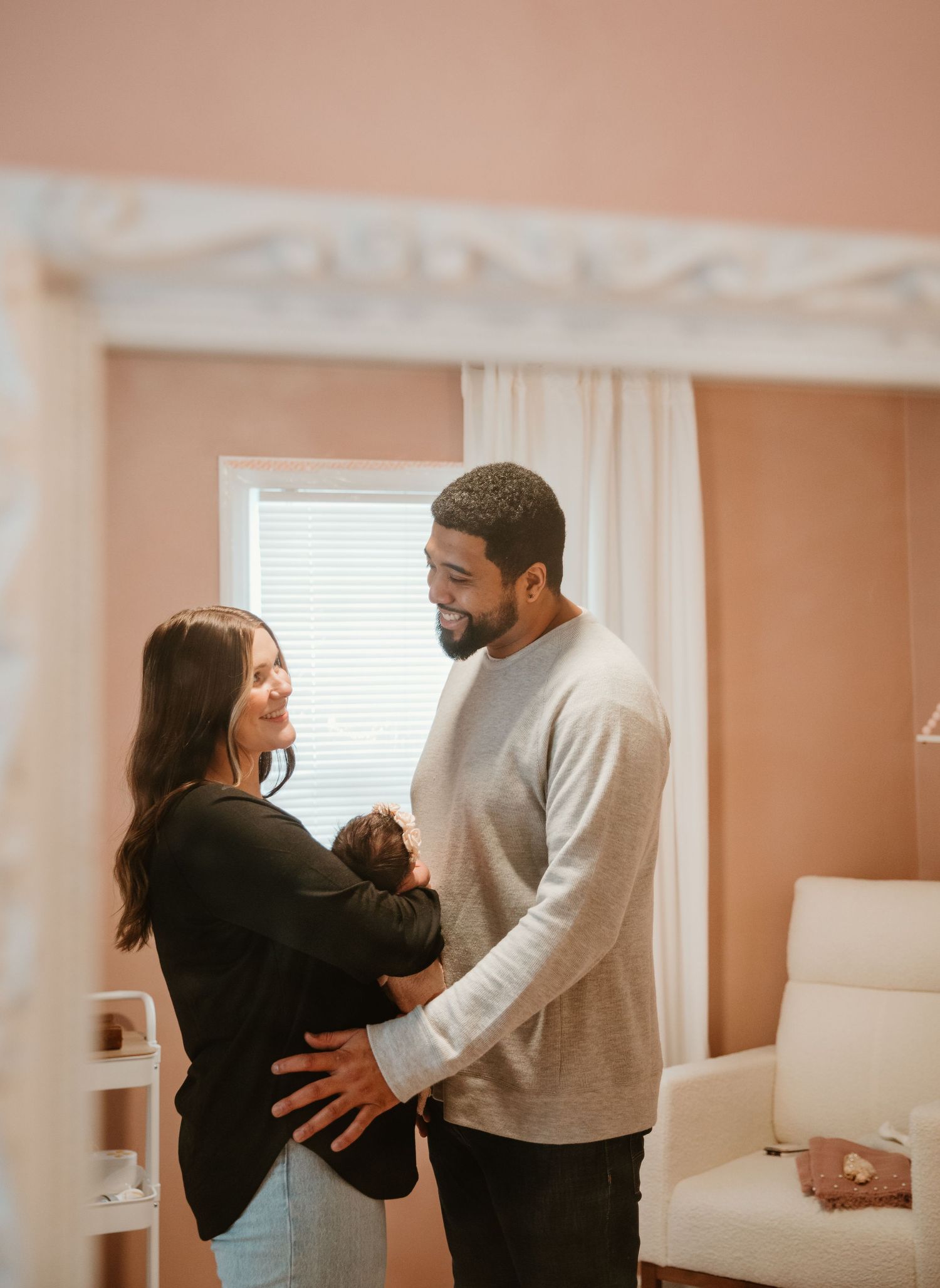 A couple dances together in a room with peach-colored walls and white curtains.