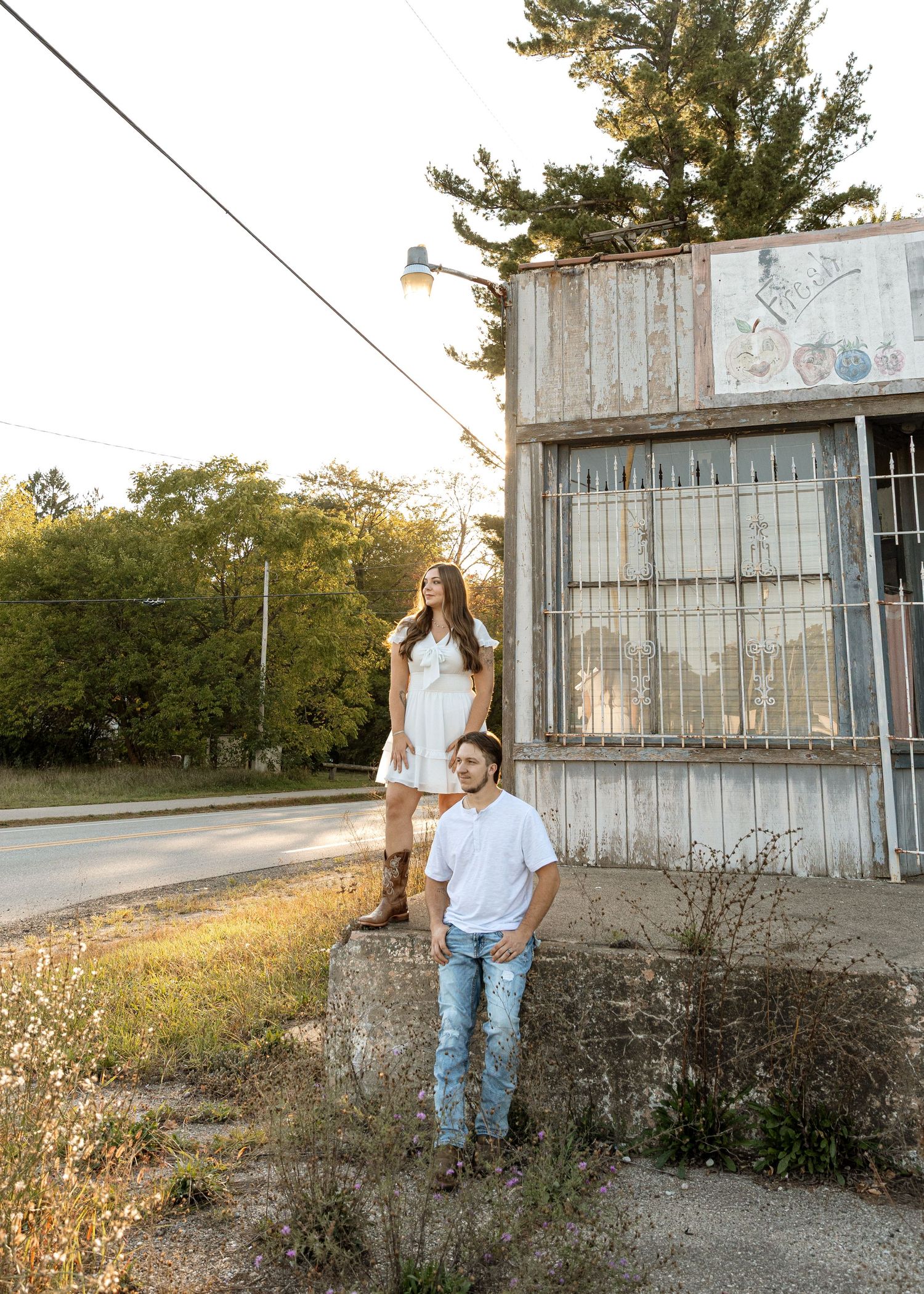 Sunset engagement photo at rustic produce store with couple at different levels.