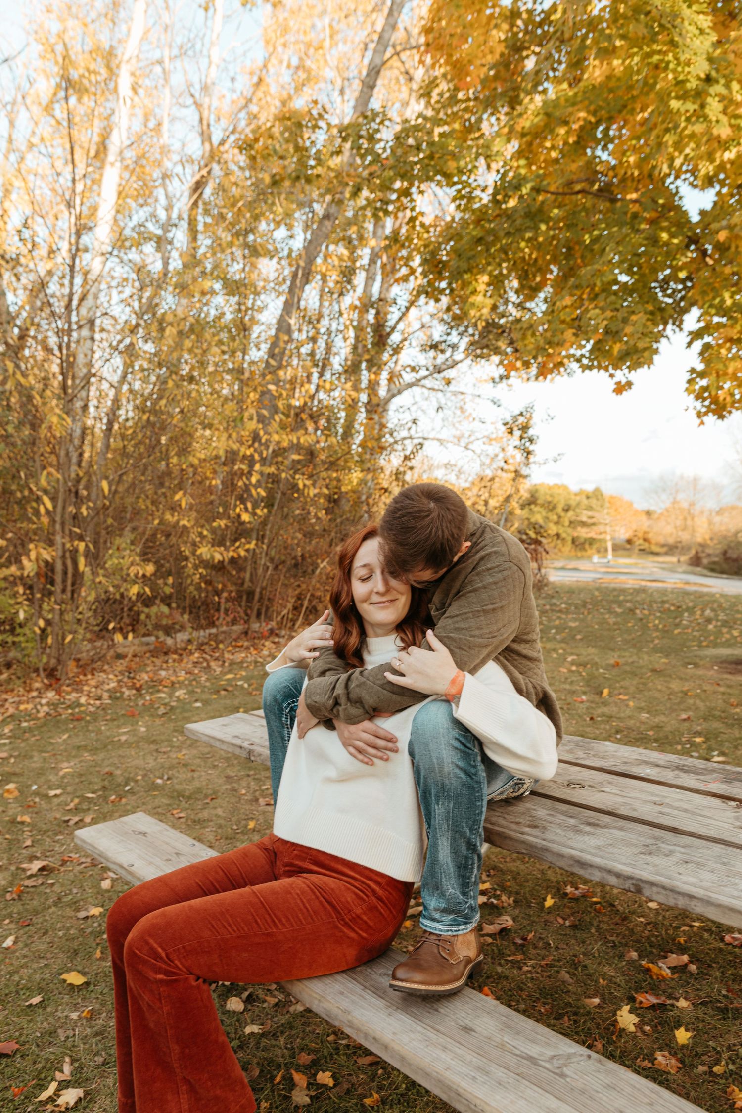A romantic autumn moment captured on a wooden bench with warm fall colors in the background.