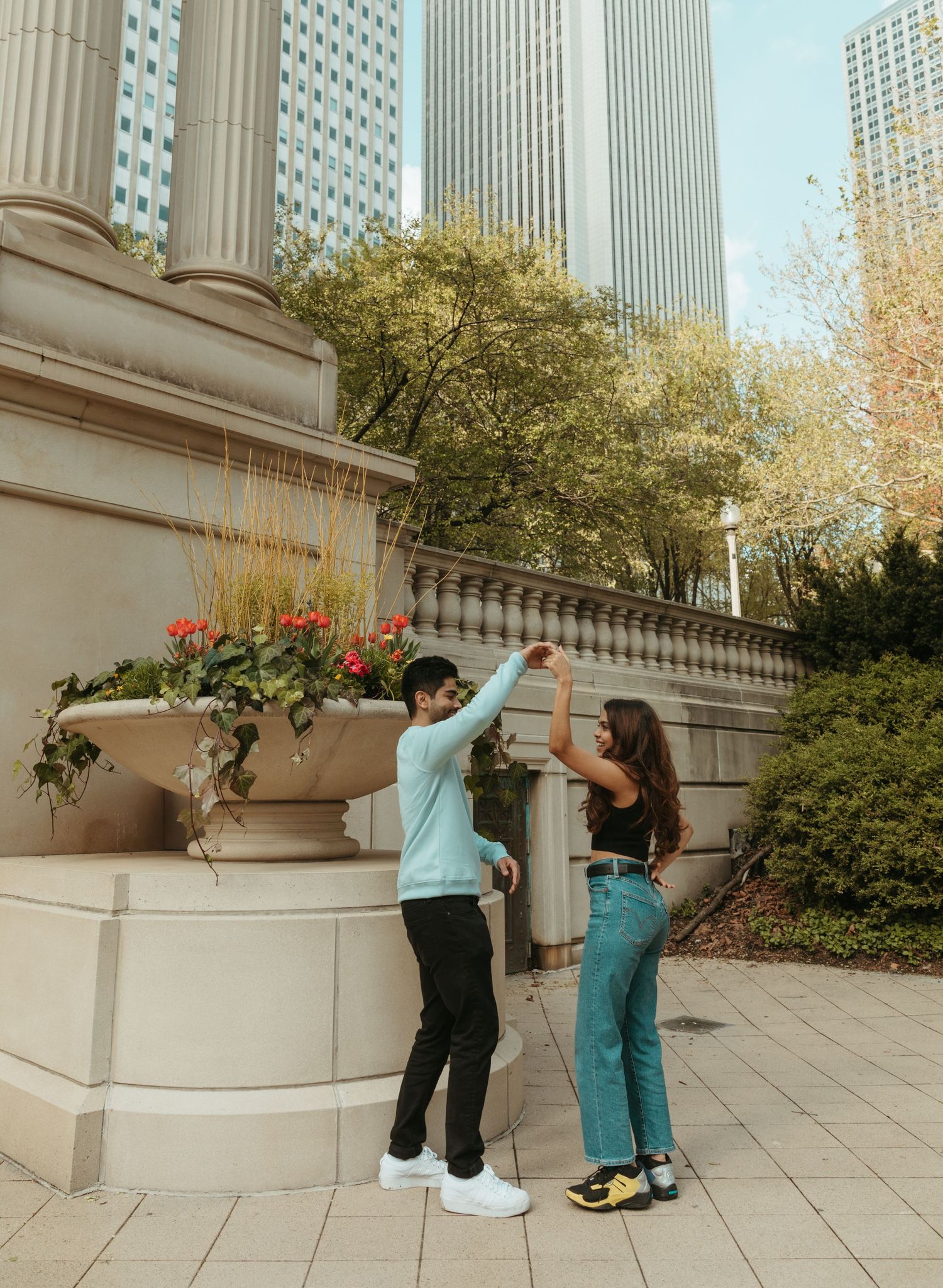 Couple playing and posing near architectural columns and planters in downtown area.