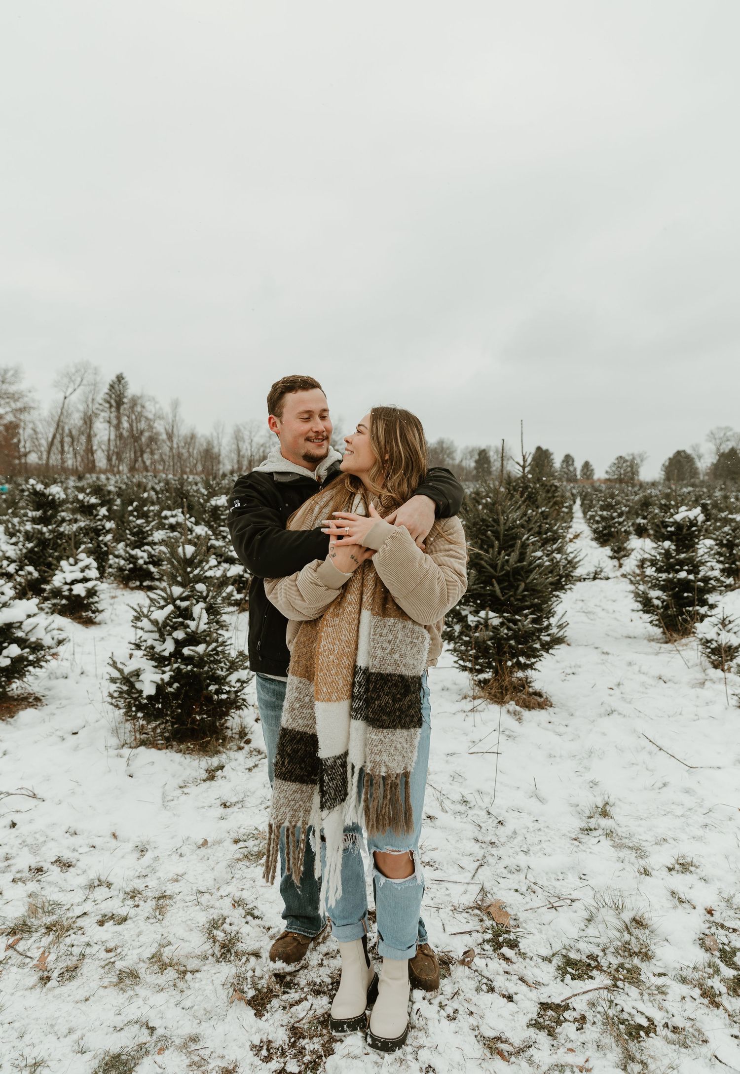 Joyful reaction during winter proposal among snow-covered evergreen trees.