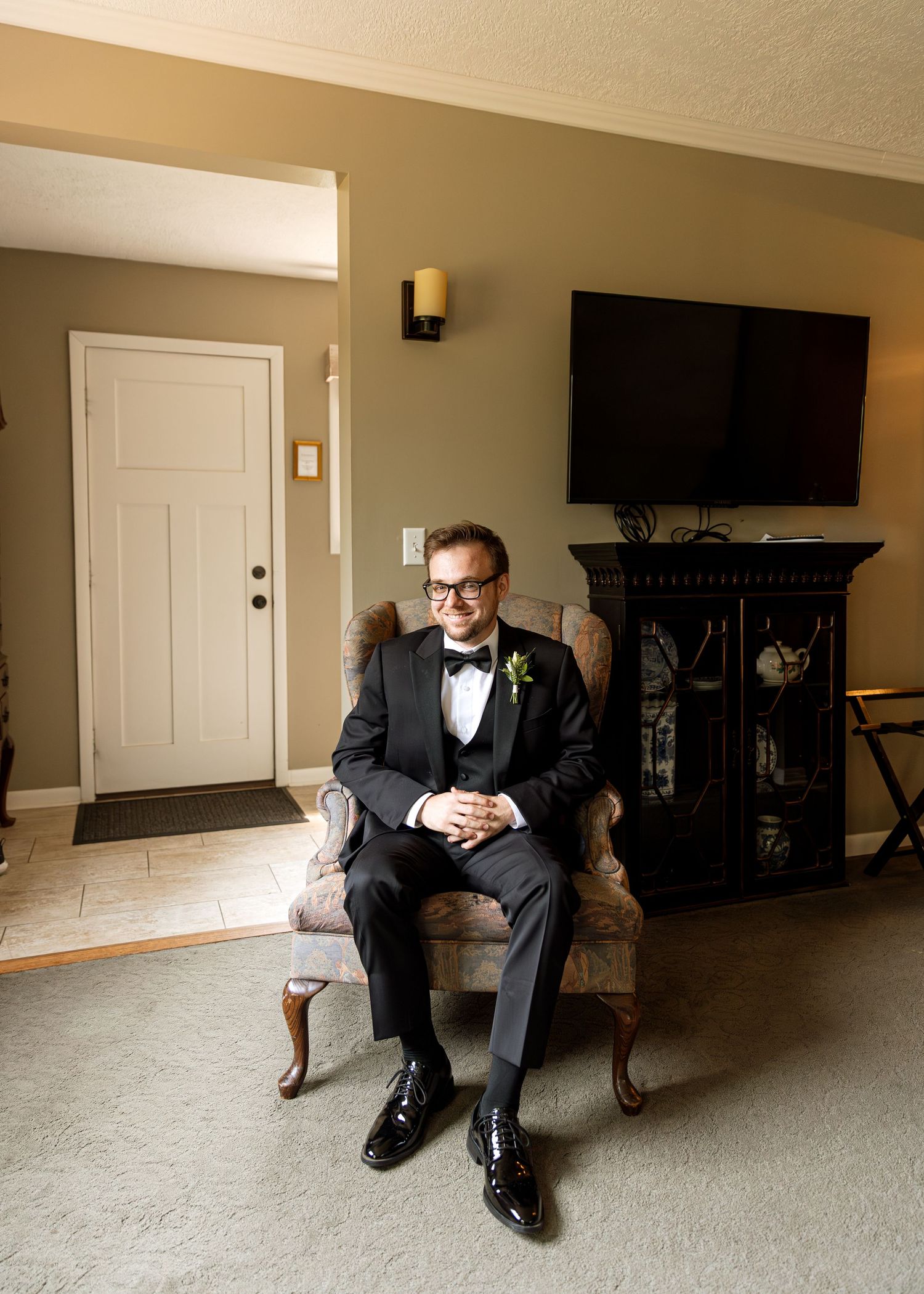 A person in formal attire sits alone in different poses on a bench in an empty room.