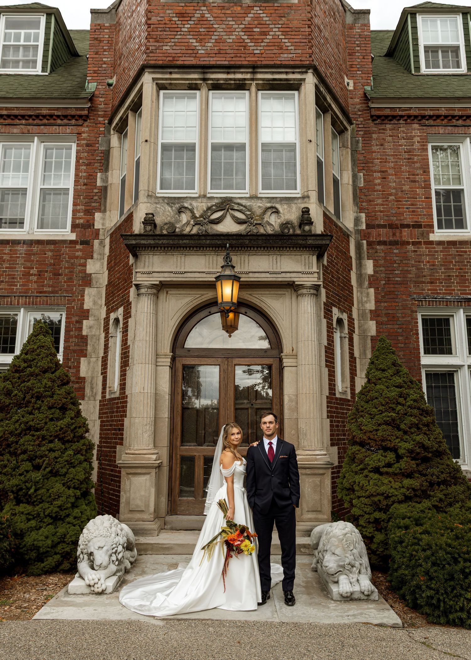 Couple poses for formal wedding photos at an ornate brick building entrance.