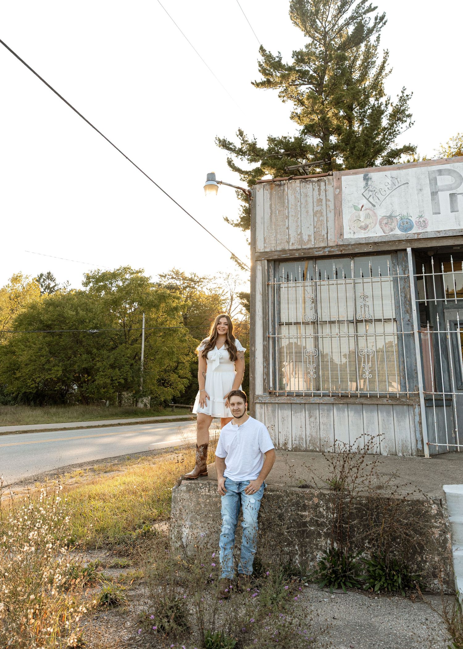 Couple poses at different heights outside weathered storefront building.