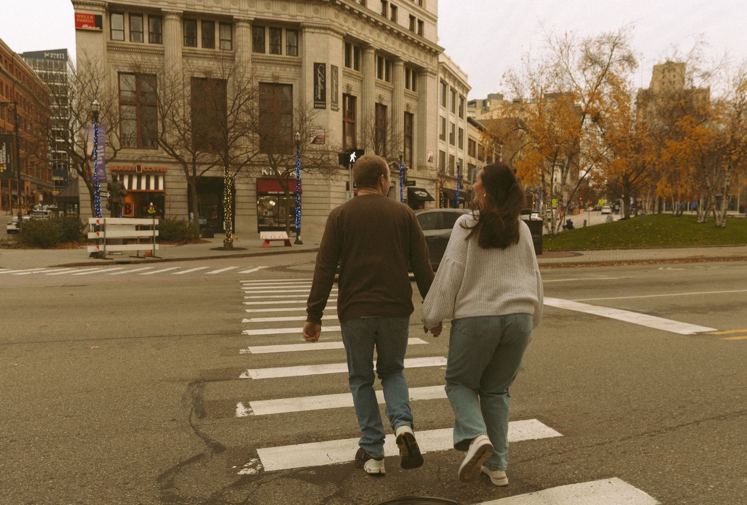 People walking across a sepia-toned urban plaza with historic buildings in the background.