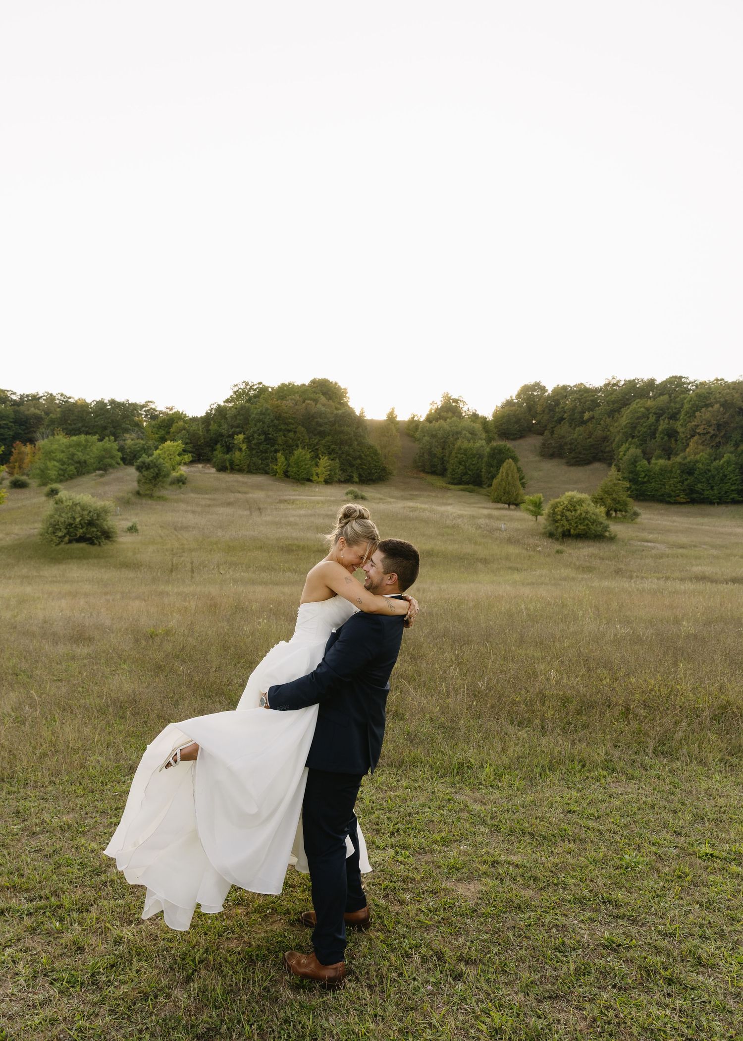 Romantic wedding poses captured in a scenic meadow during golden hour.
