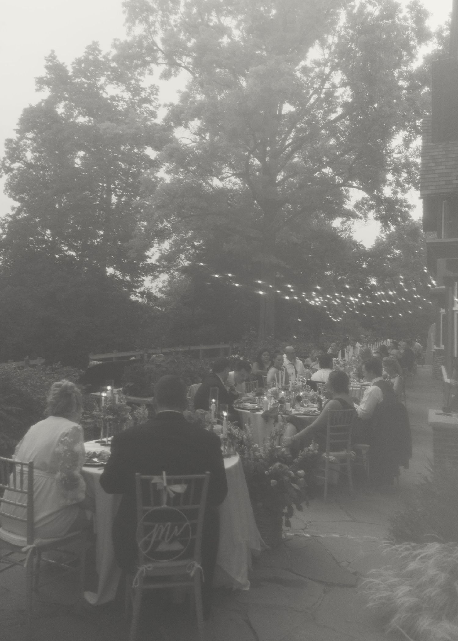 Outdoor wedding reception setup at dusk with tables and chairs arranged on a patio.