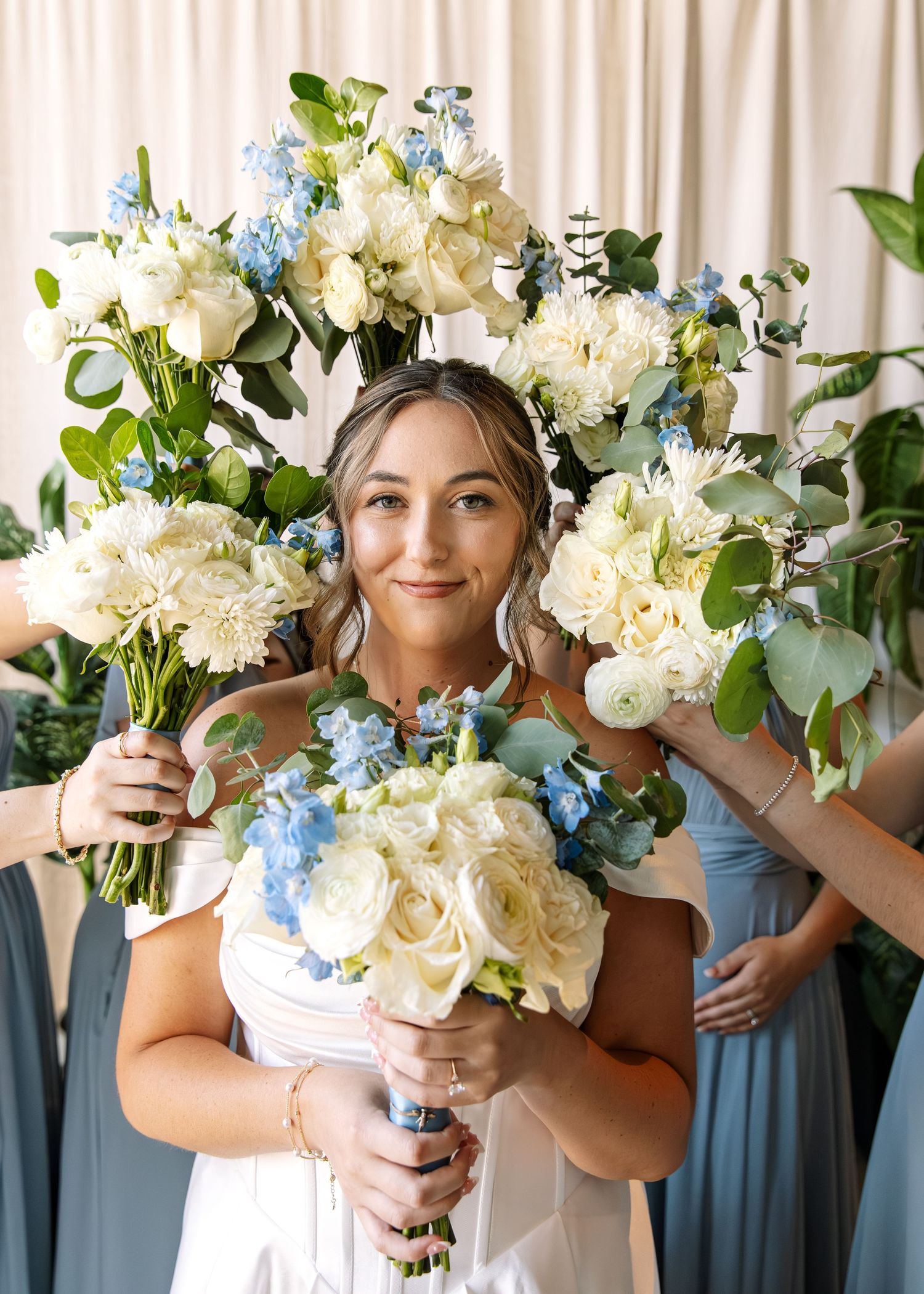 Beautiful wedding bouquet featuring white and blue flowers held against white backdrop.