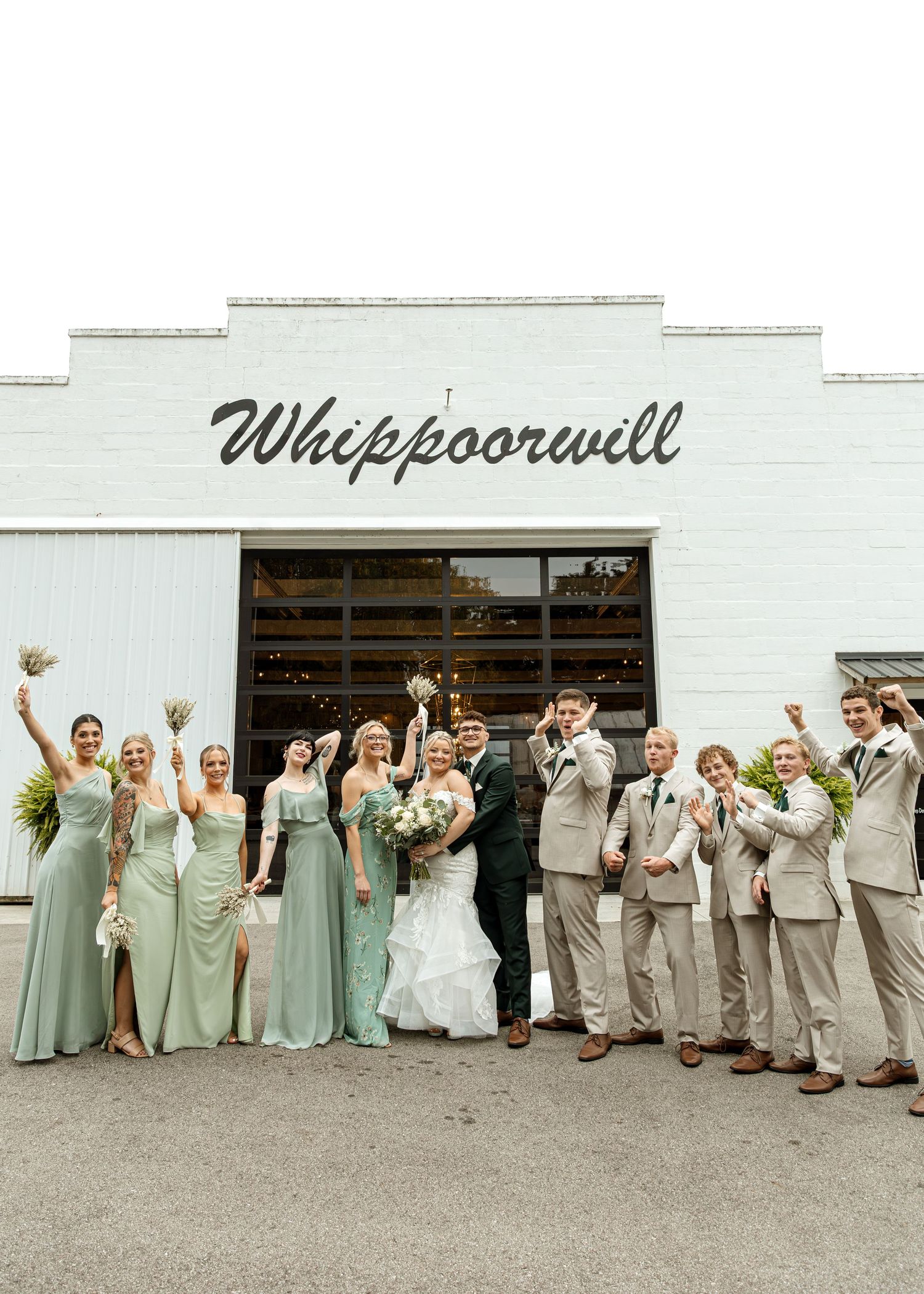 Wedding party celebrates outside Whippoorwill venue with bridesmaids in sage and groomsmen in tan.