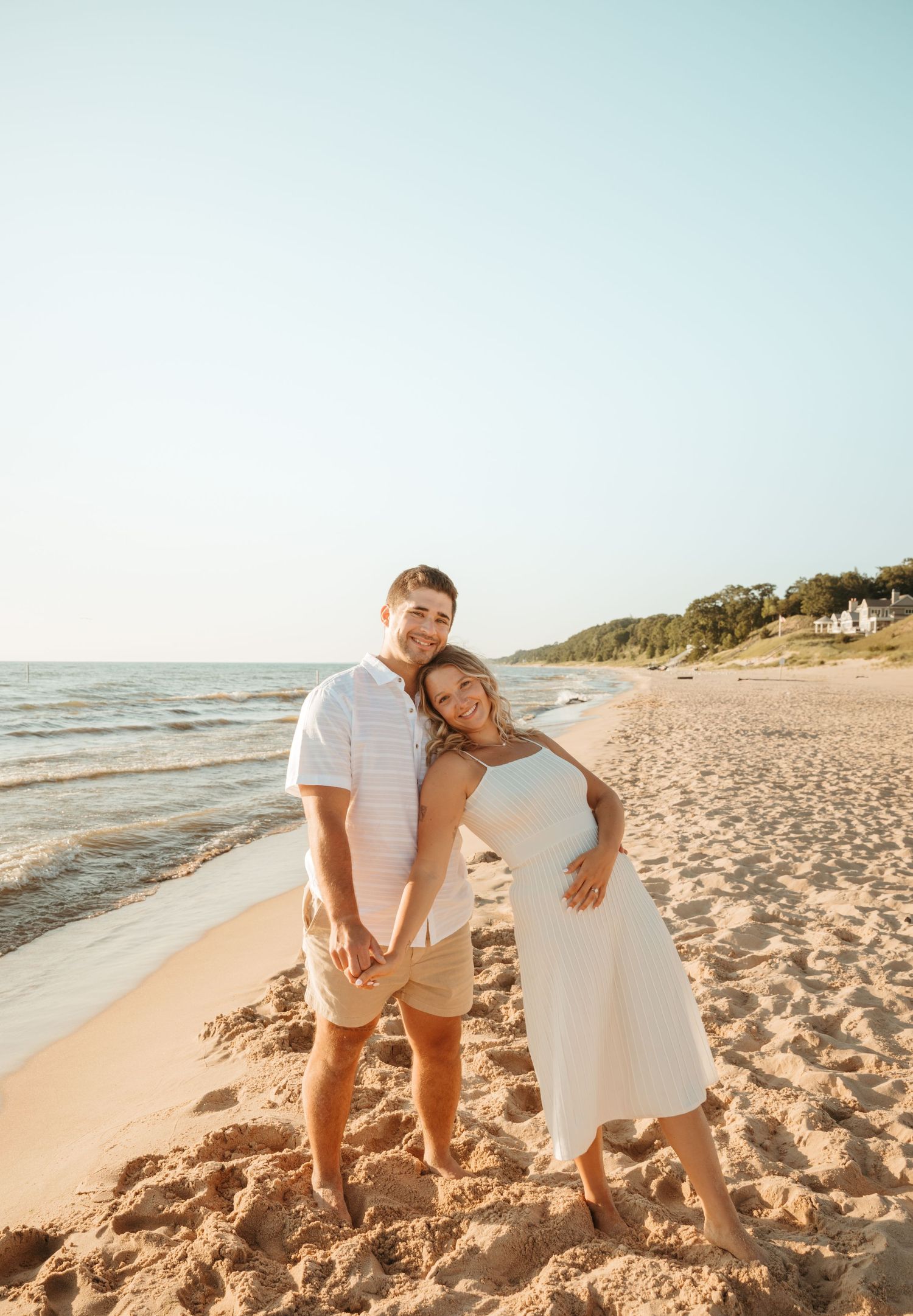 Couple laughing together on sandy beach during golden hour photoshoot.