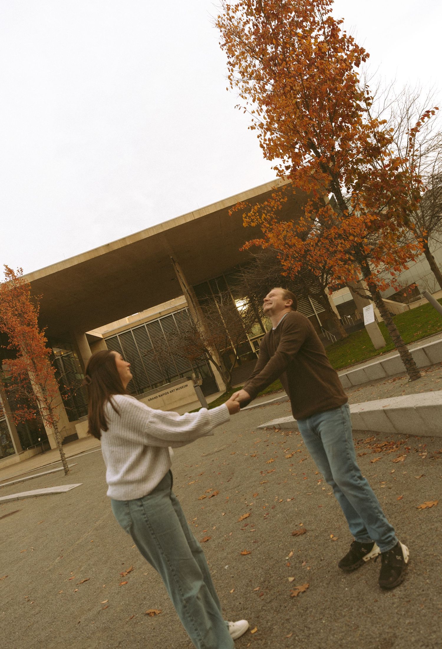 A playful sequence of two people running towards each other in a courtyard with fall foliage.