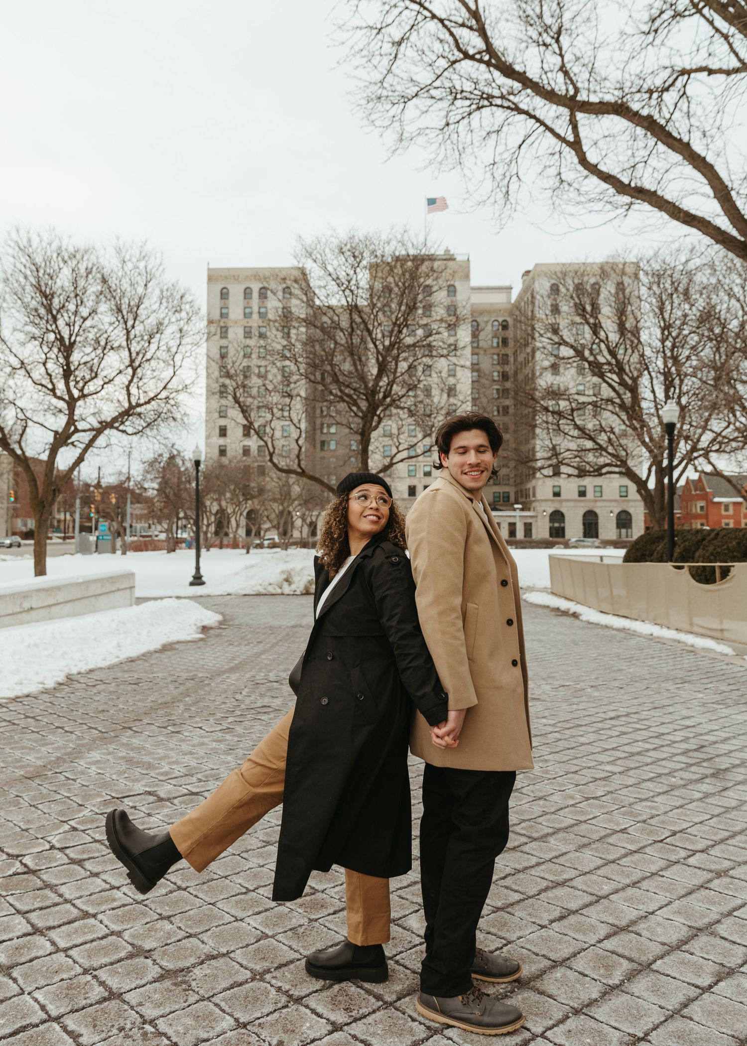 A series of playful poses between a couple on a winter day in an urban setting.